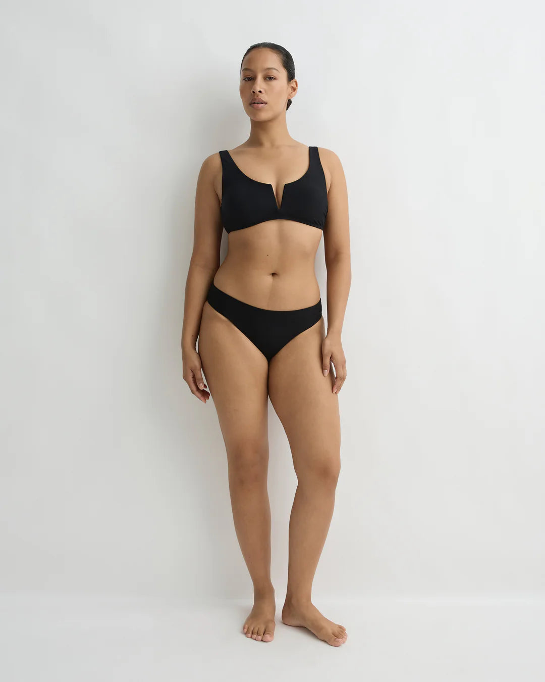 Woman wearing a black bikini against a white background