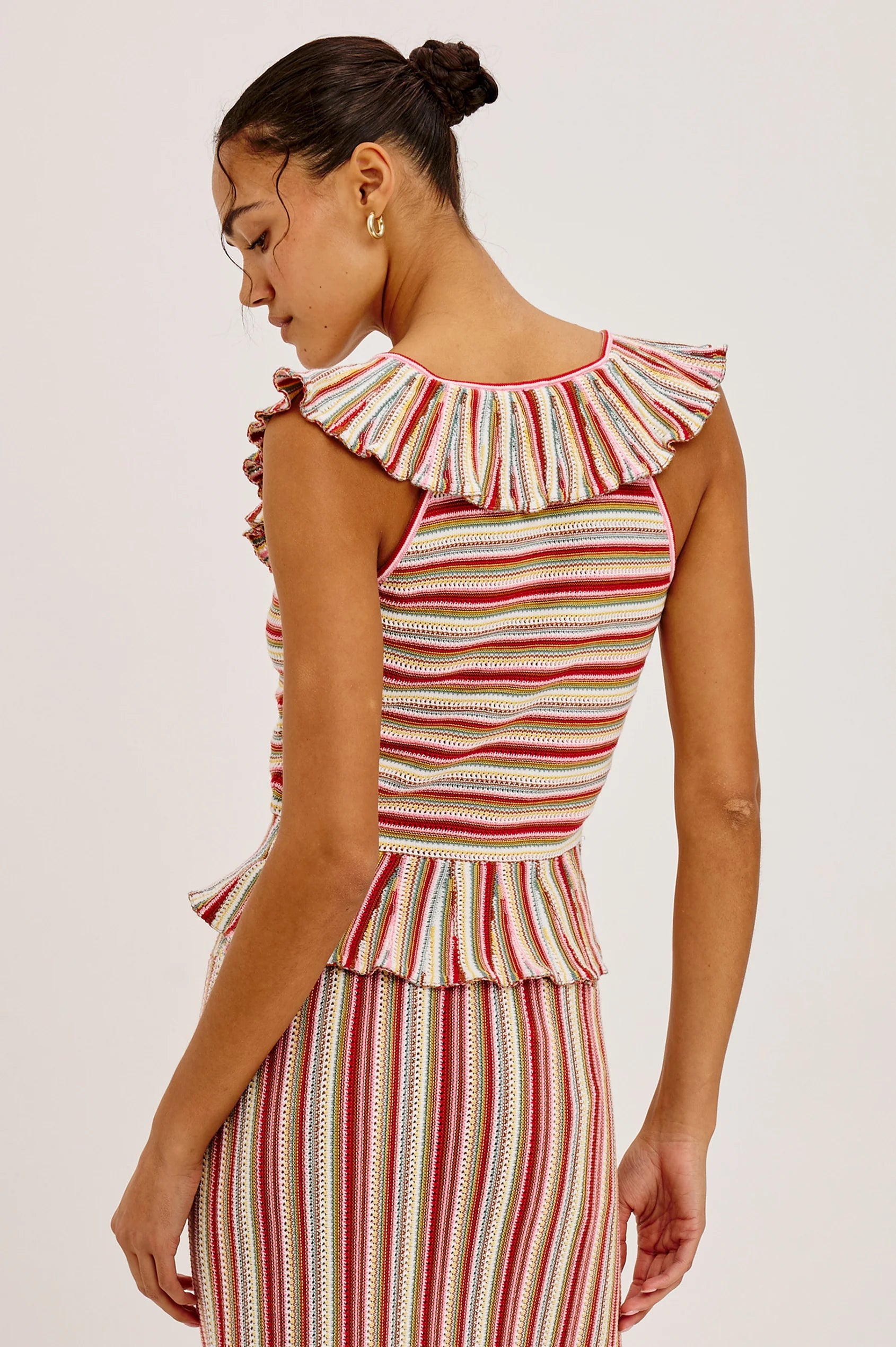 Woman wearing a colorful striped dress with ruffled shoulders on a white background