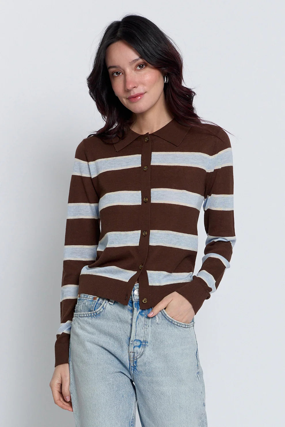 A woman wearing a brown and light gray striped button-up cardigan with a polo collar, paired with light-wash jeans, against a plain light gray background.