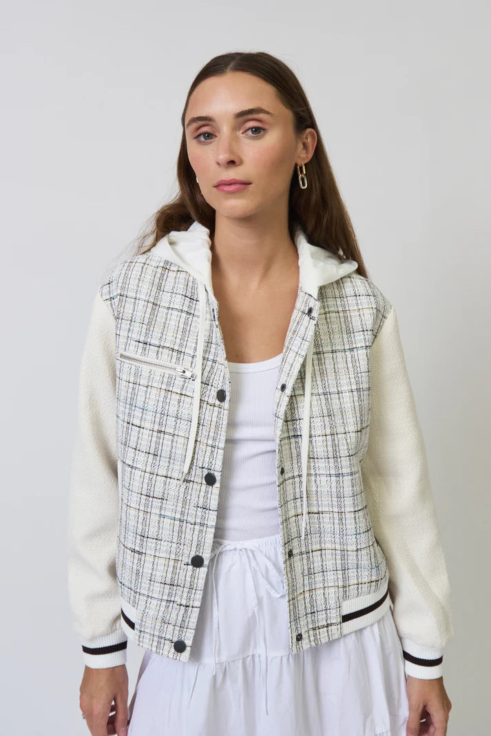 Woman wearing a plaid jacket over a white top and skirt on a plain background