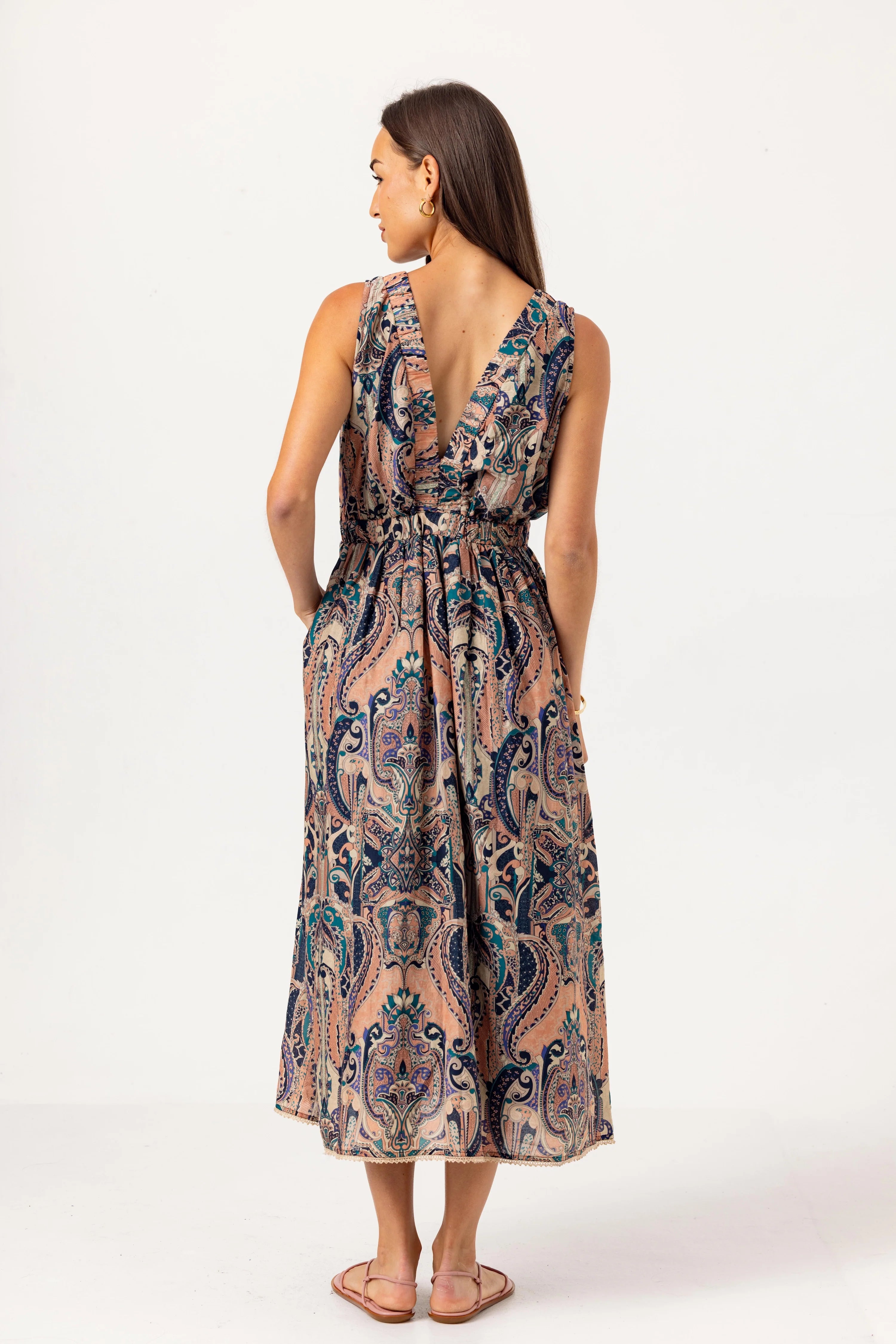 Woman wearing a patterned dress with an open back on a white background