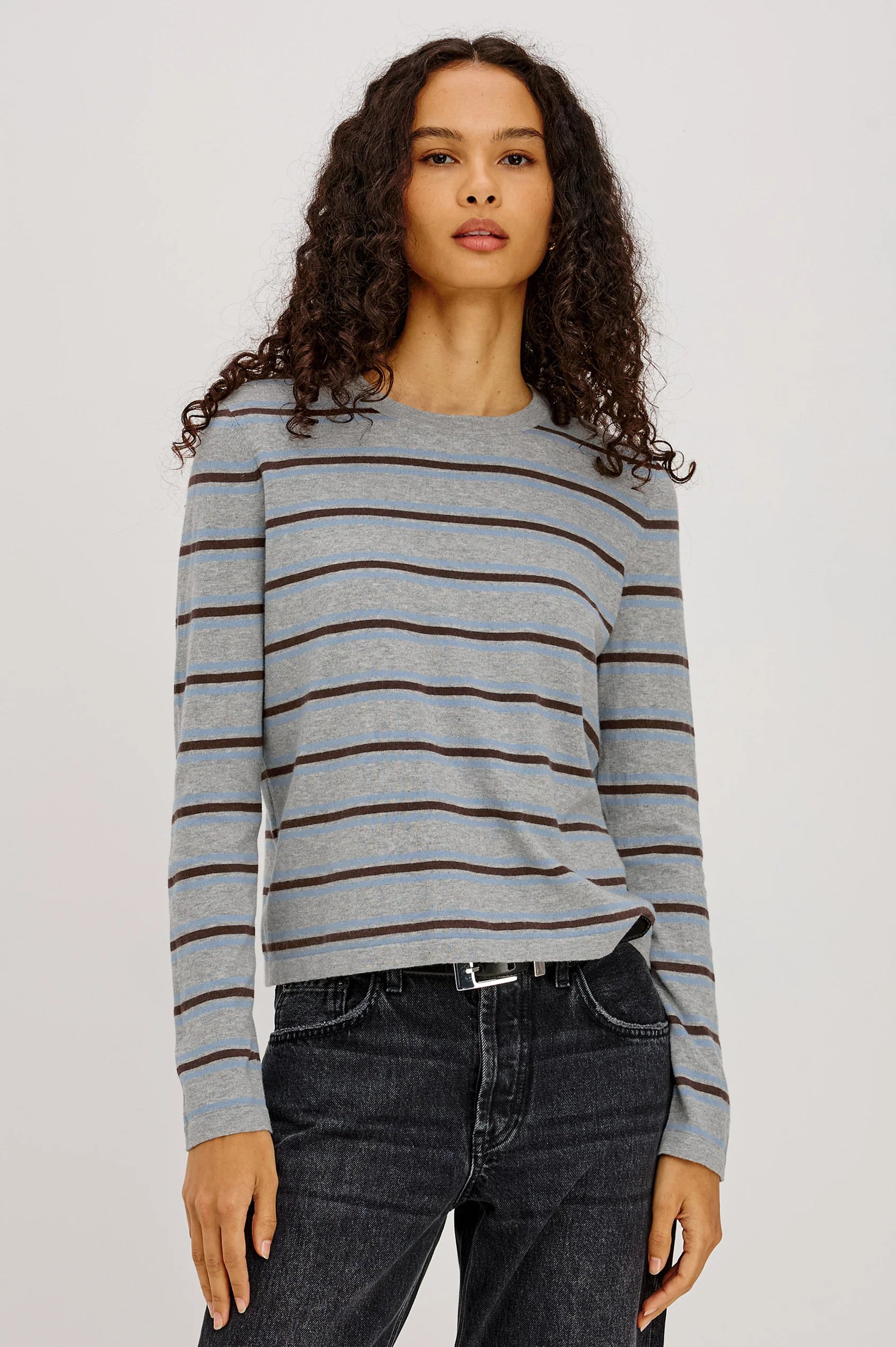 Woman wearing a striped sweater and jeans on a plain background