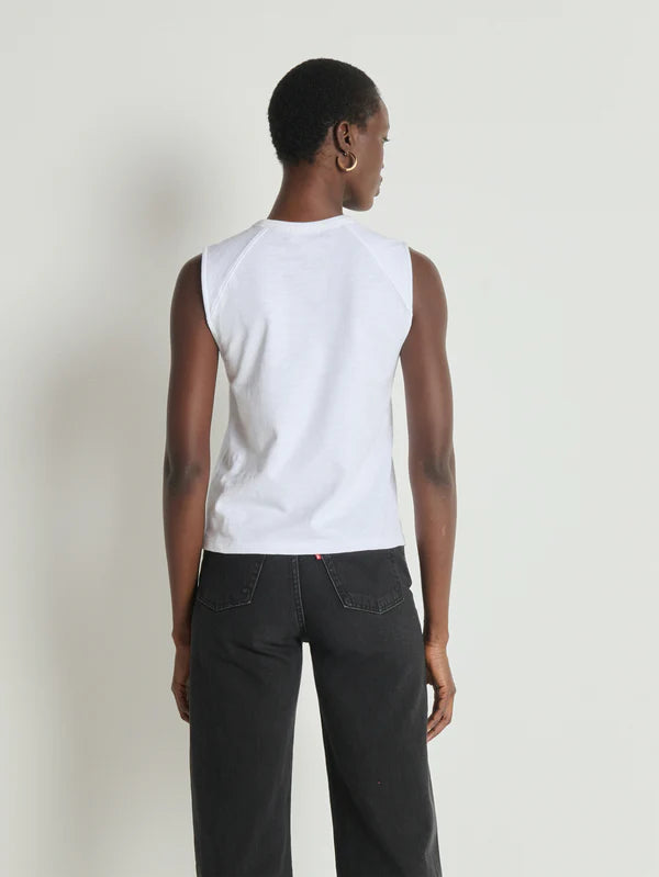 Person wearing a white sleeveless shirt and black pants against a plain background