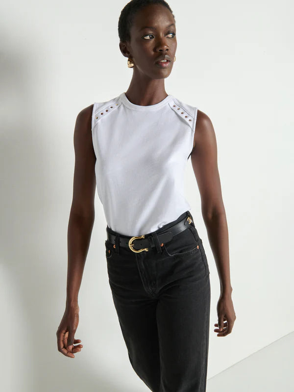 Woman wearing a white sleeveless top with cut-out shoulders and black pants on a white background