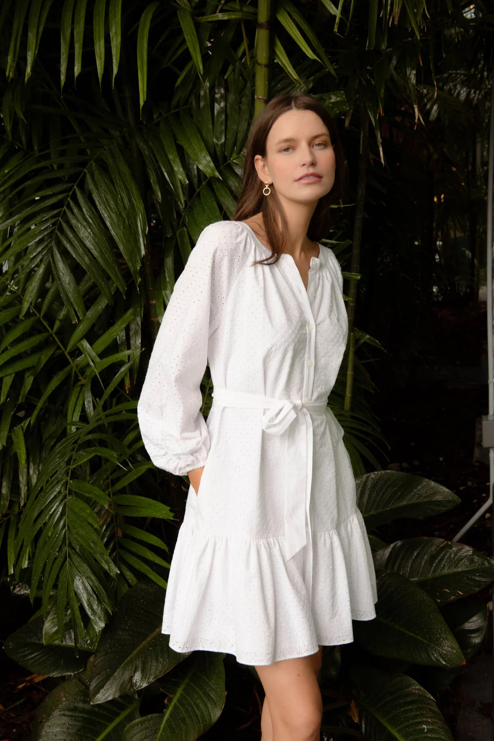 Woman wearing a white dress standing among green foliage