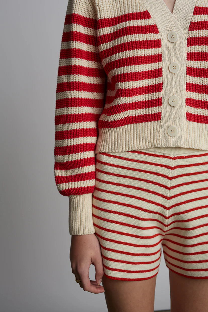 Person wearing a red and white striped sweater and shorts on a plain background