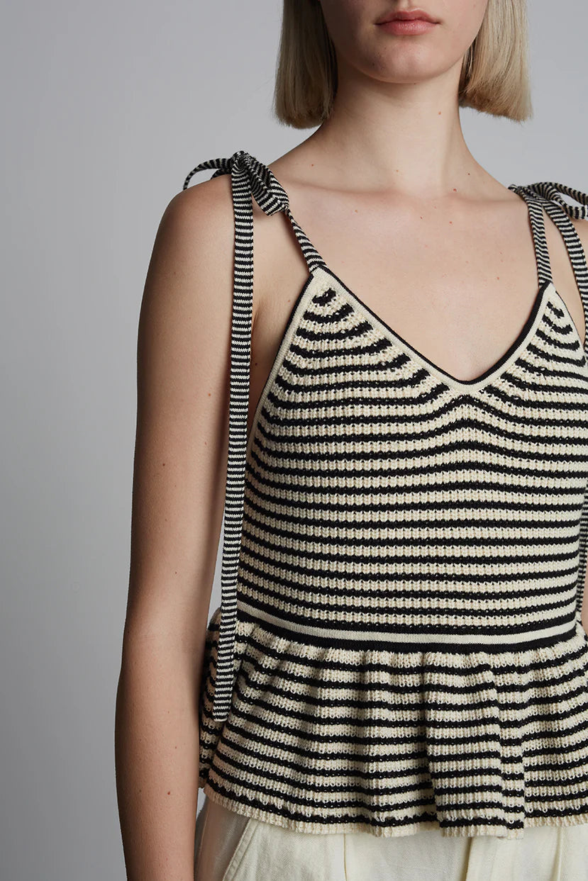 Woman wearing a black and white striped tank top against a plain background