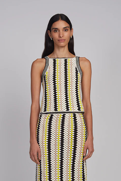 Woman wearing a sleeveless dress with black, white, and yellow pattern on a gray background