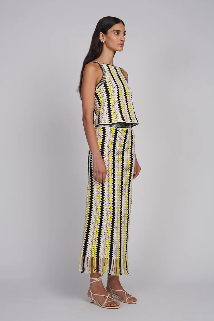 Woman wearing a sleeveless top and striped pants on a gray background