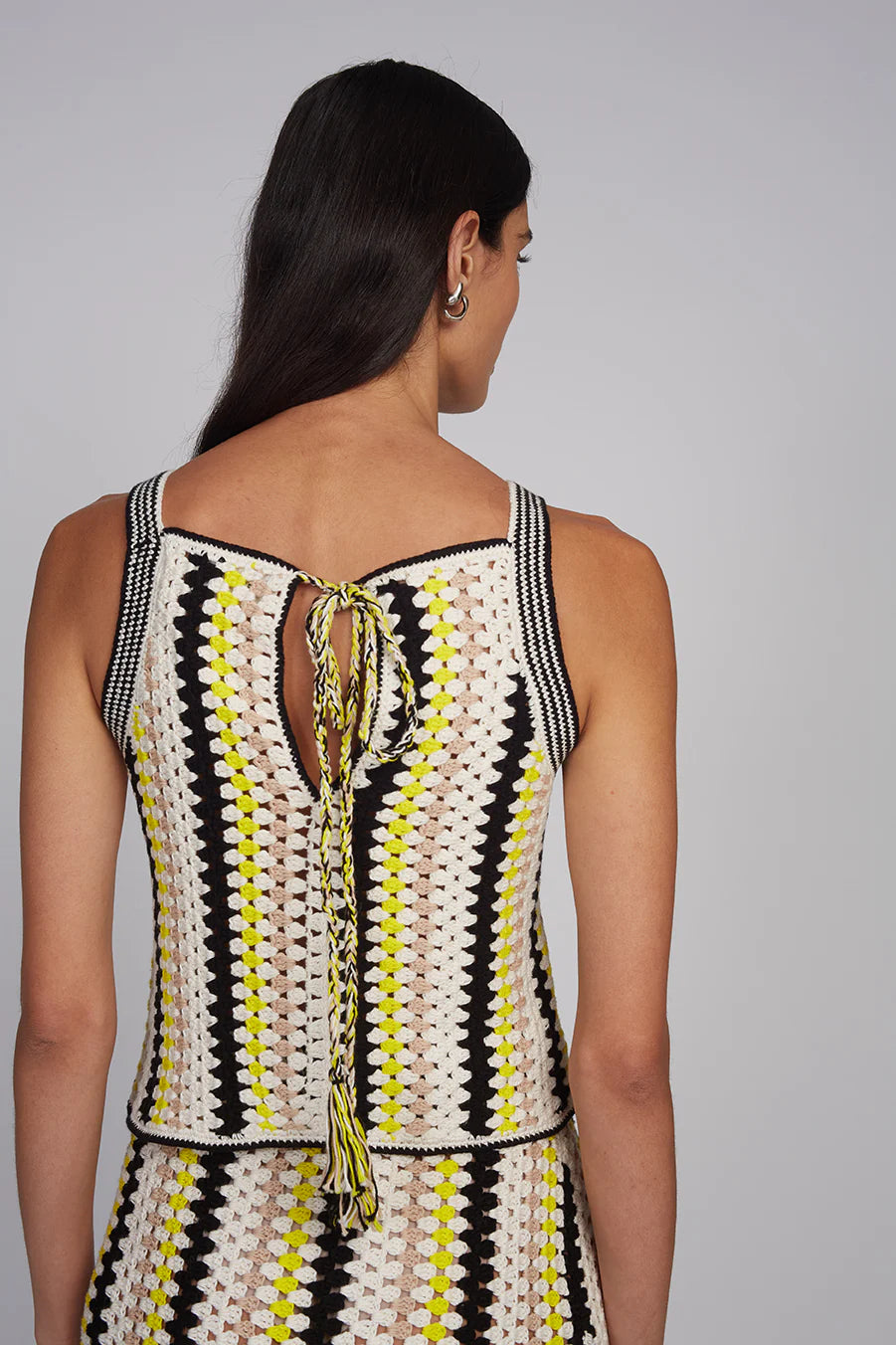 Woman wearing a sleeveless dress with a geometric pattern on a gray background