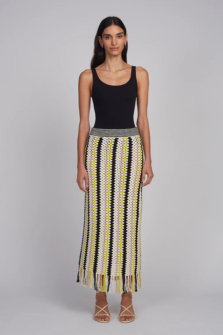 Woman wearing a black tank top and a patterned skirt on a gray background