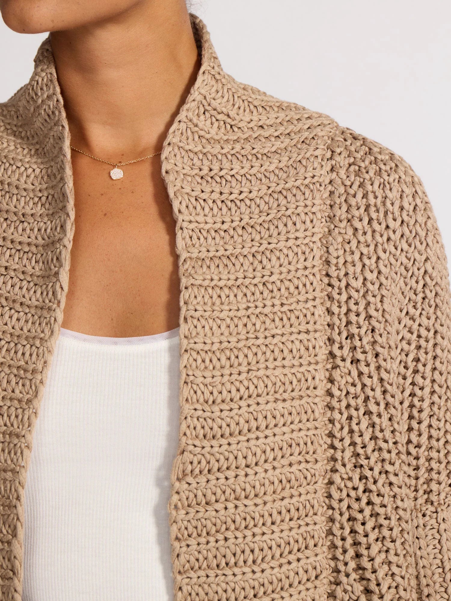 Beige knitted cardigan worn by a person on a white background