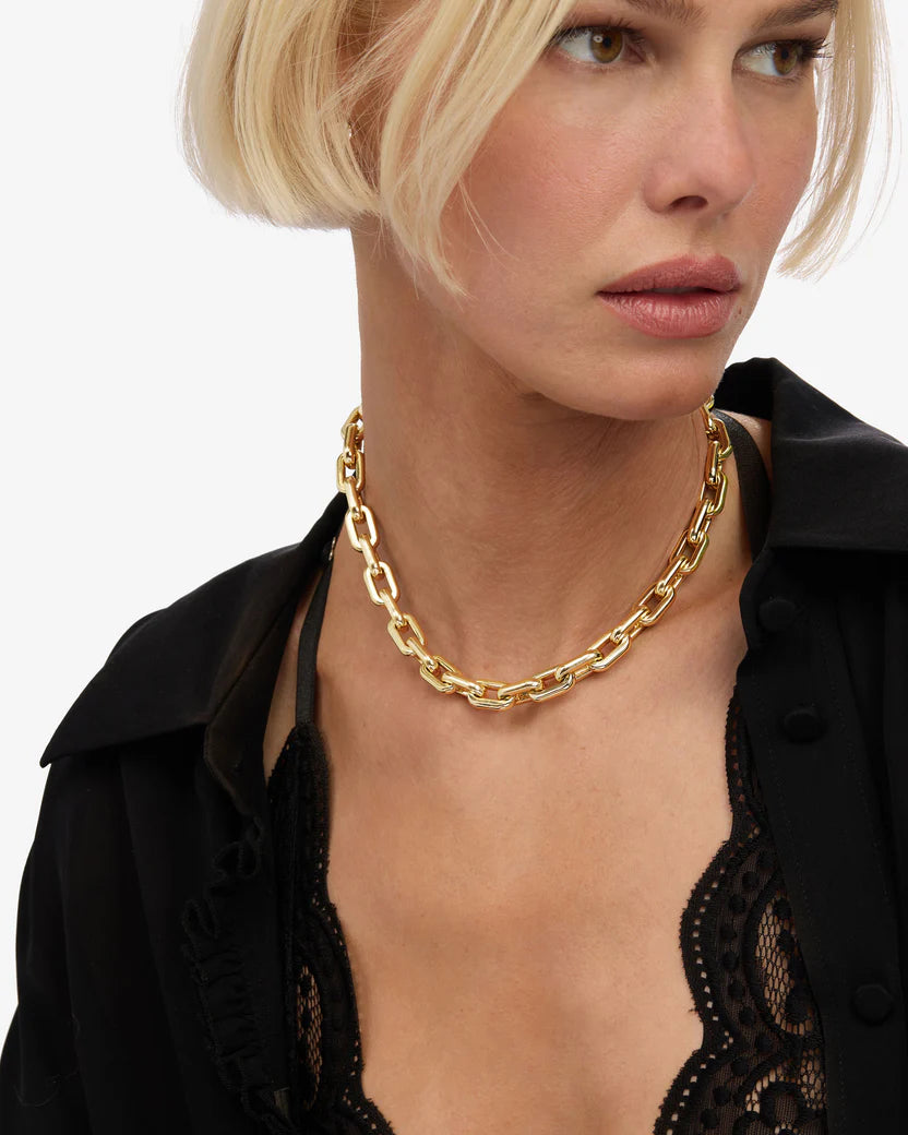 Woman wearing a gold chain necklace against a white background