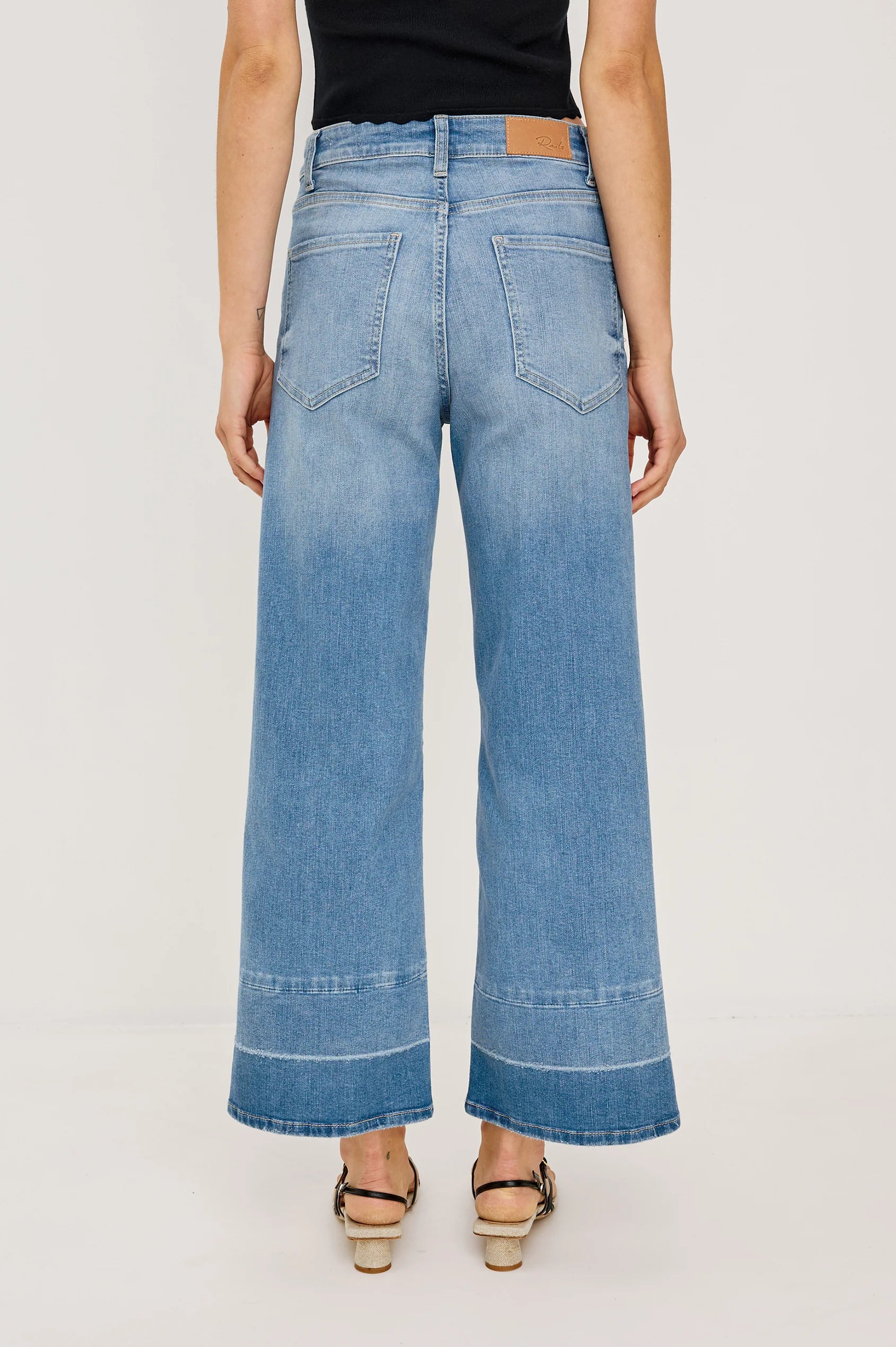 Person wearing blue wide-leg jeans on a plain background