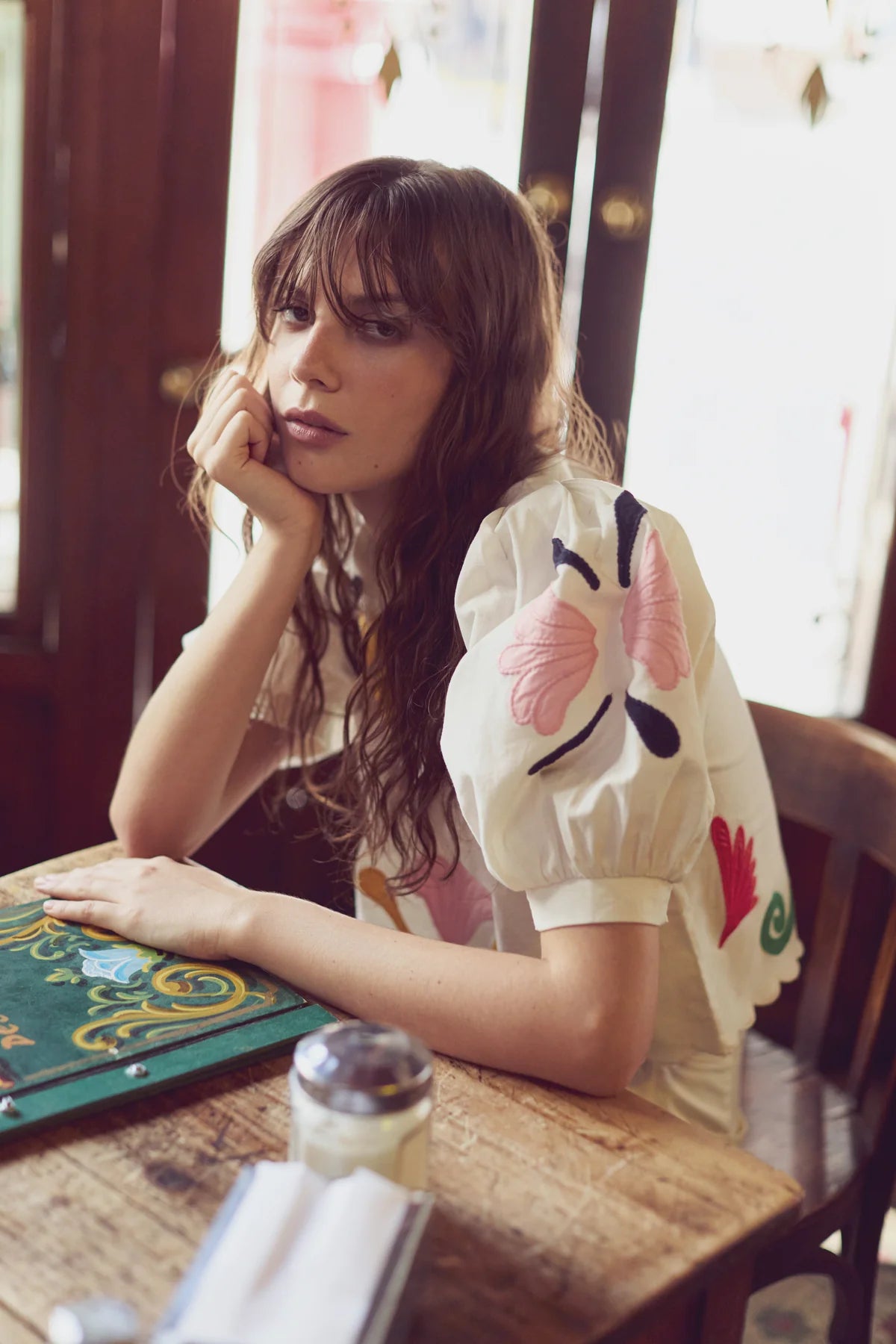 Woman sitting at a table with a colorful shirt in a casual setting