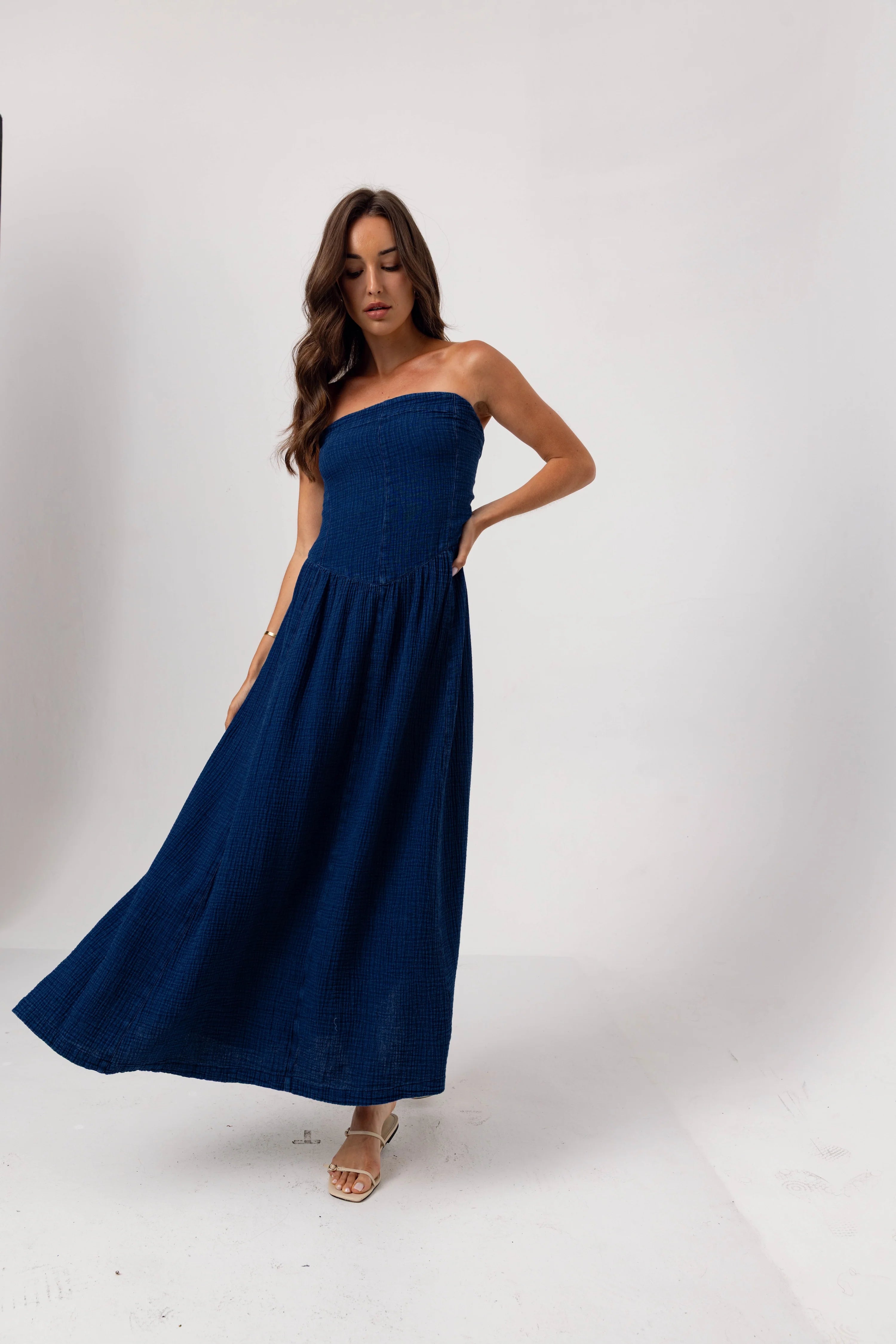 Woman wearing a strapless navy blue dress on a white background