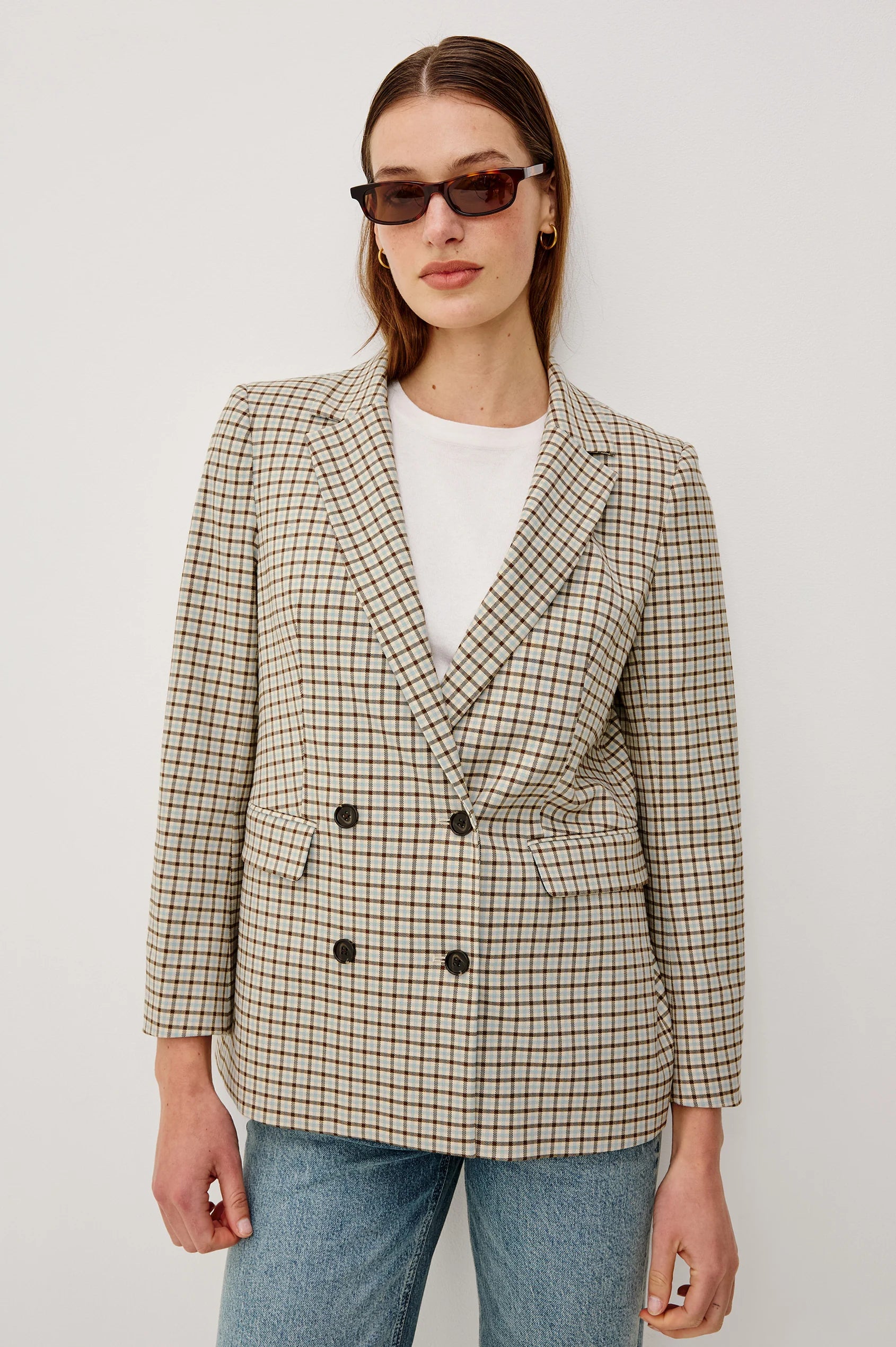Person wearing a checkered blazer and sunglasses against a white background