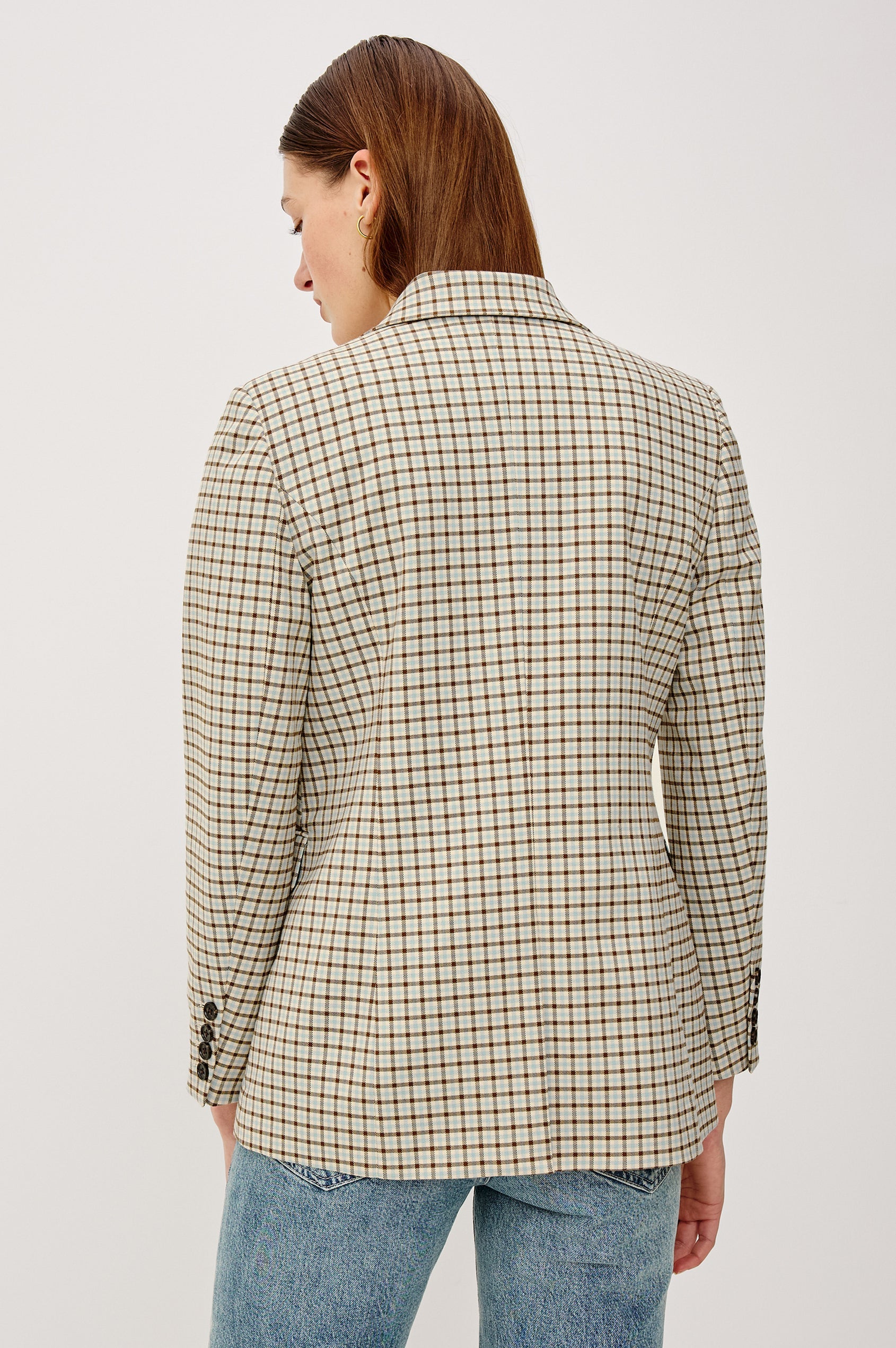 Person wearing a checkered blazer on a plain background