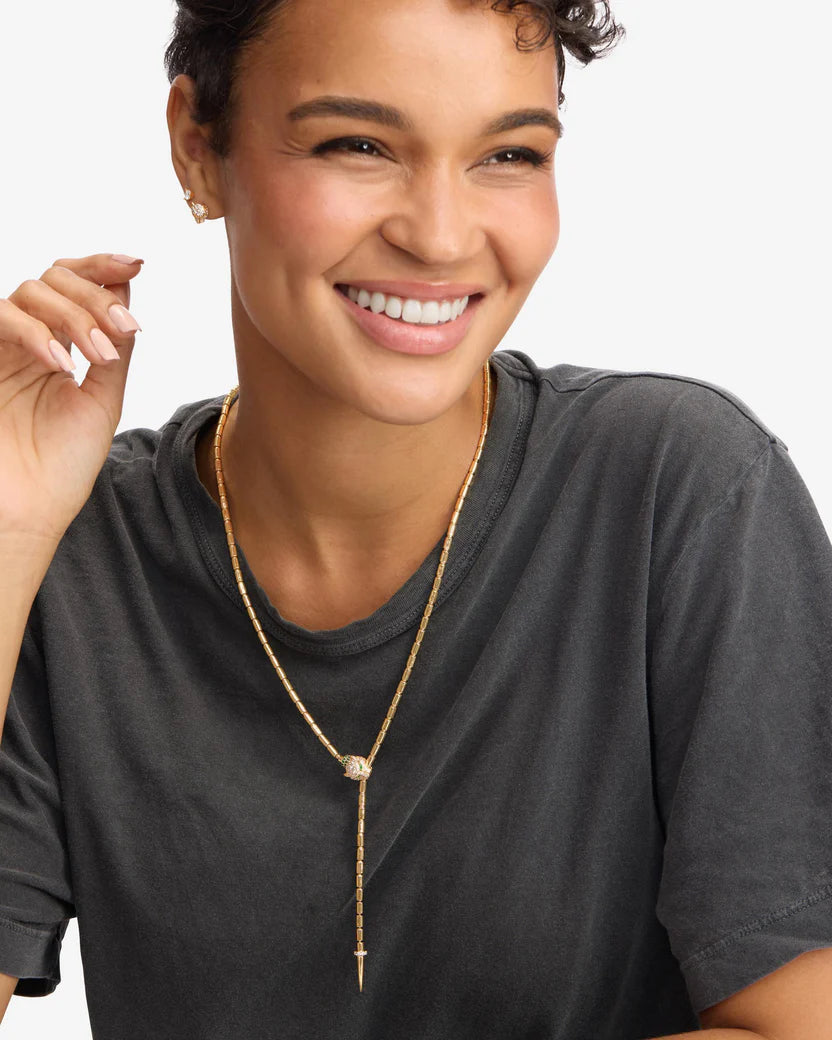 Woman wearing a gold necklace against a plain background