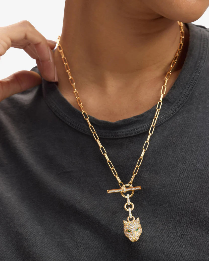 Gold chain necklace with a pendant worn by a person on a plain background