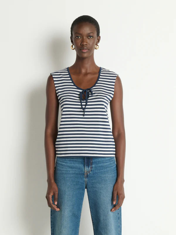 Woman wearing a striped tank top and jeans against a plain background