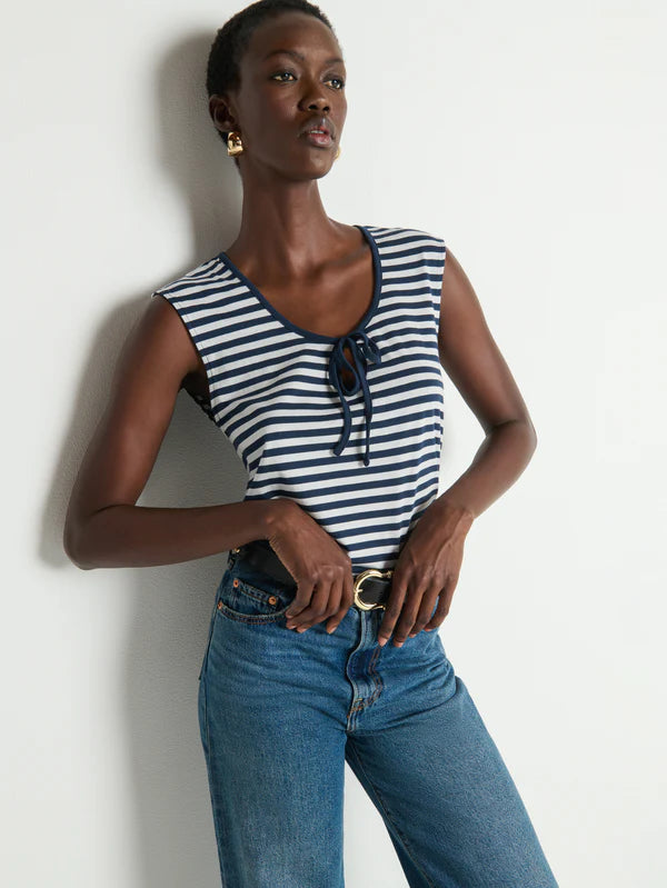 Woman wearing a striped sleeveless top and blue jeans against a white background