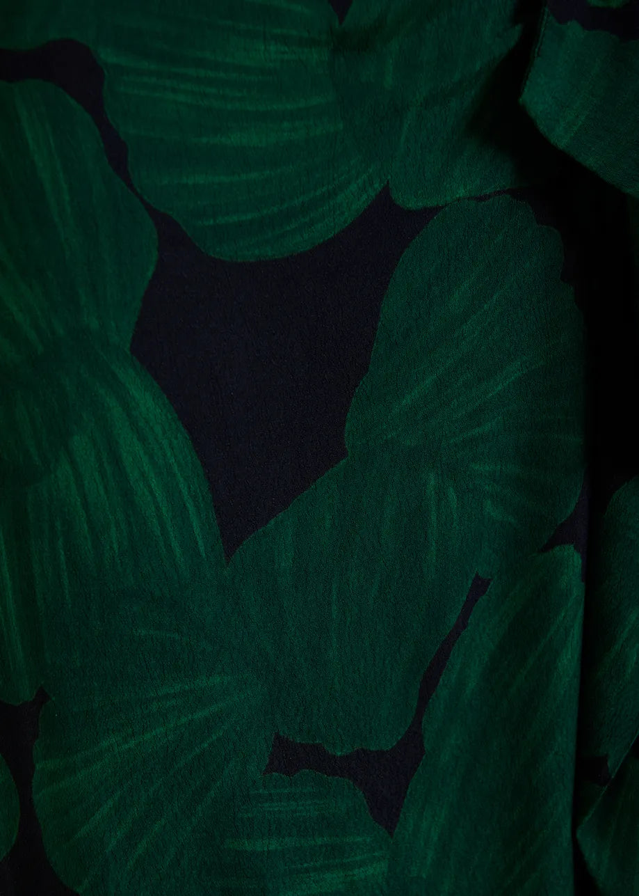A close-up of a dark green and black tropical leaf pattern, likely a fabric swatch or garment detail.