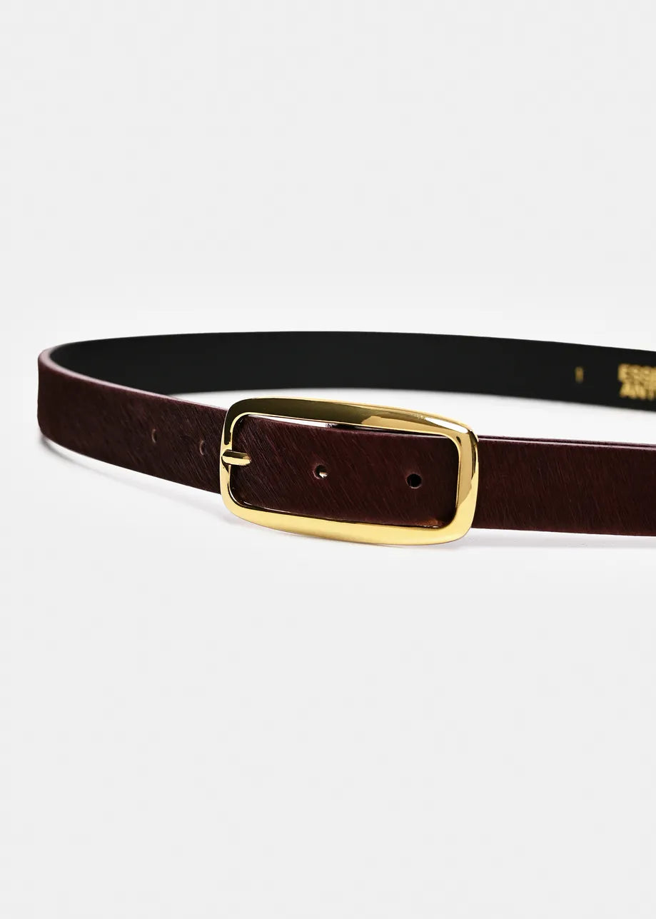 A dark brown leather belt with a gold buckle, displayed horizontally on a light gray background. The inner side of the belt is black with gold branding text that reads 'COSTUME D'EPICE'.