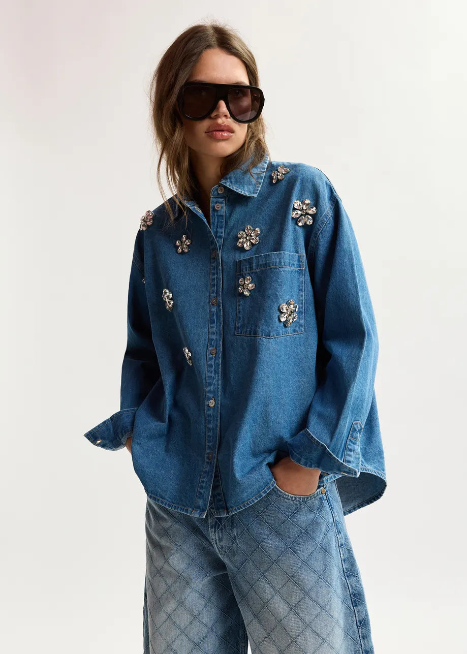 Person wearing a denim outfit with floral embellishments on a white background