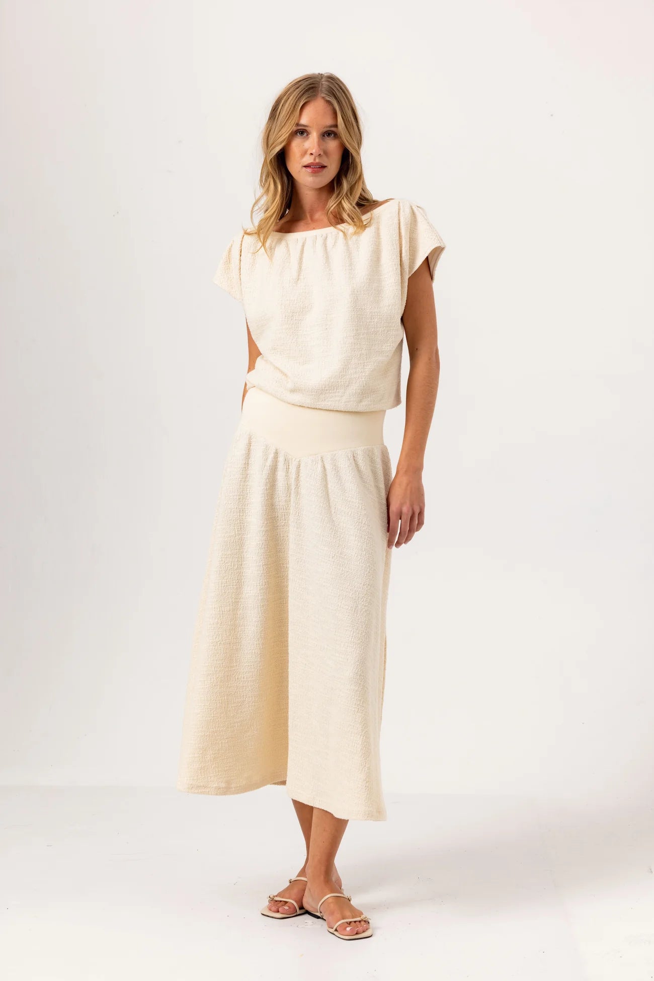 Woman wearing a cream-colored outfit on a white background