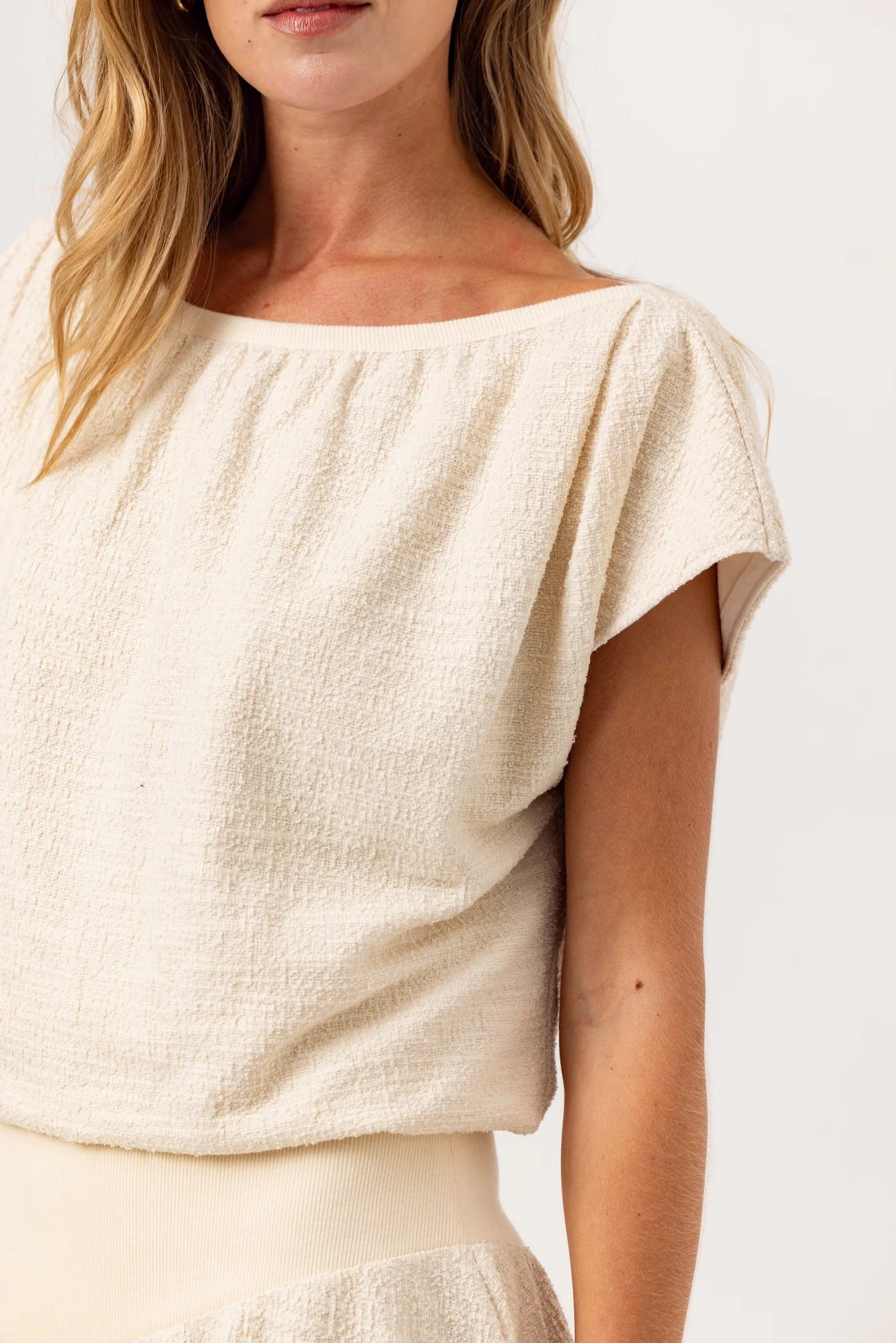 woman wearing a white cream shortsleeve shirt with white background
