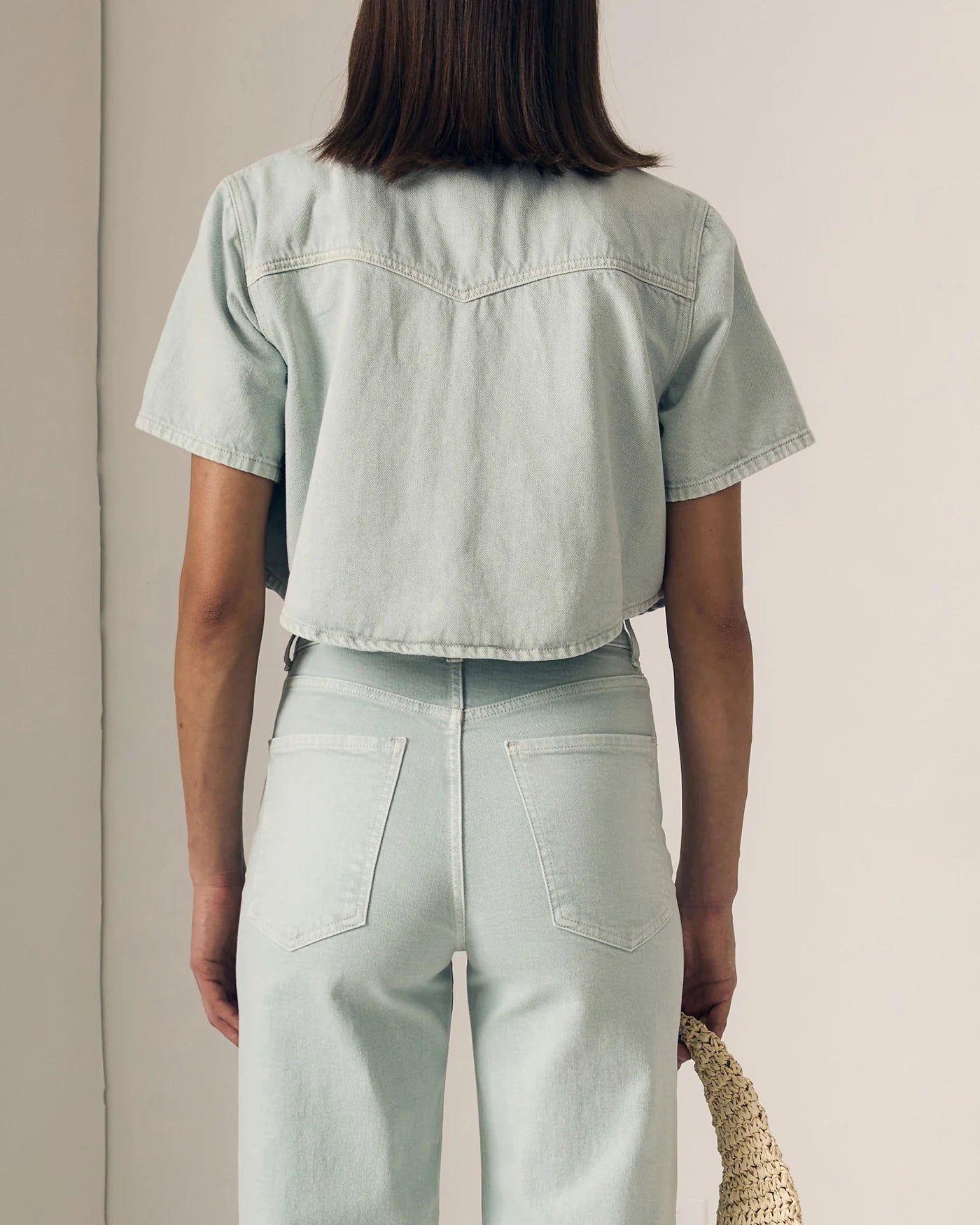 Person wearing a light green denim outfit against a neutral background