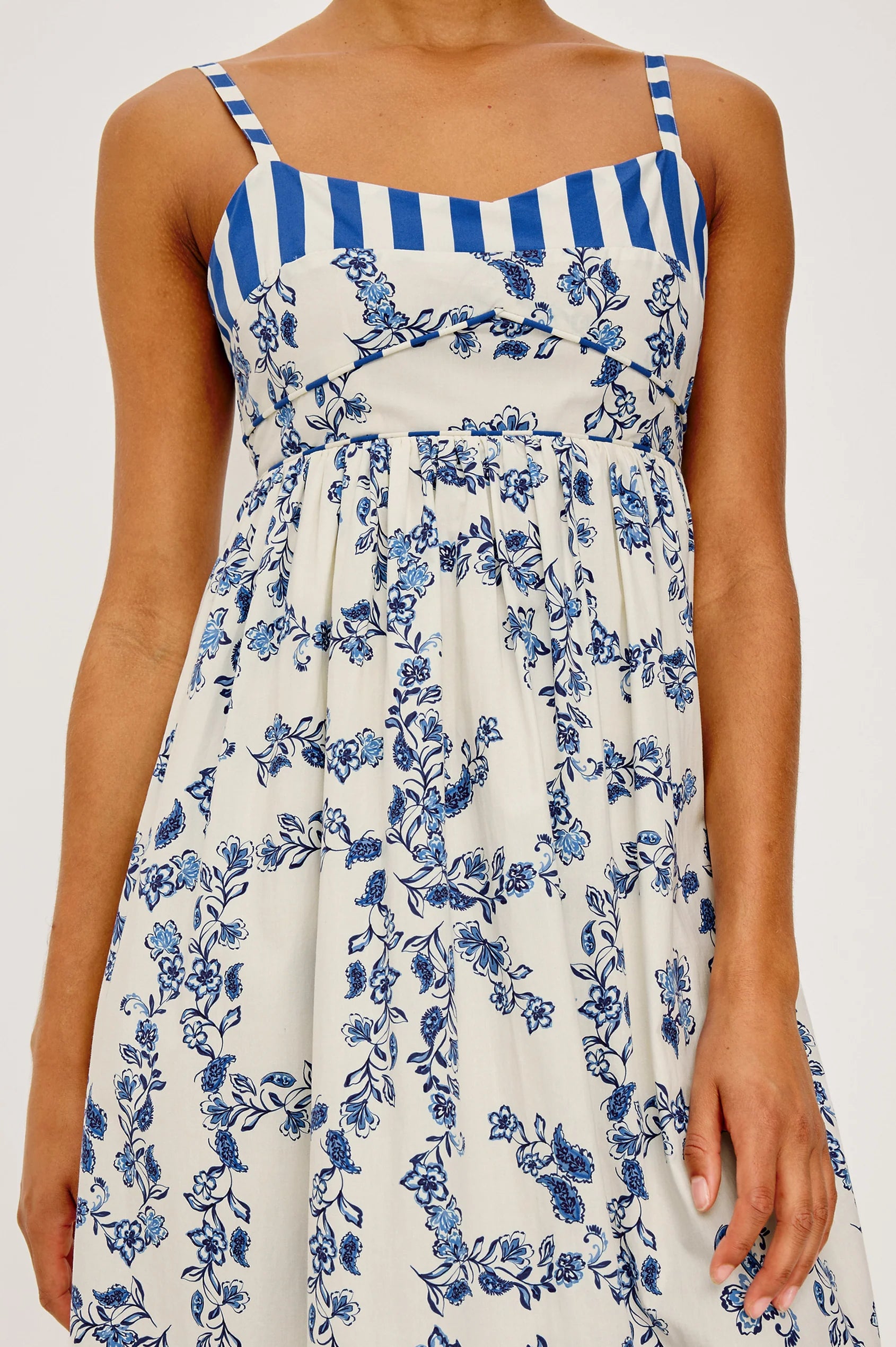 Woman wearing a blue and white striped dress with floral pattern on a white background