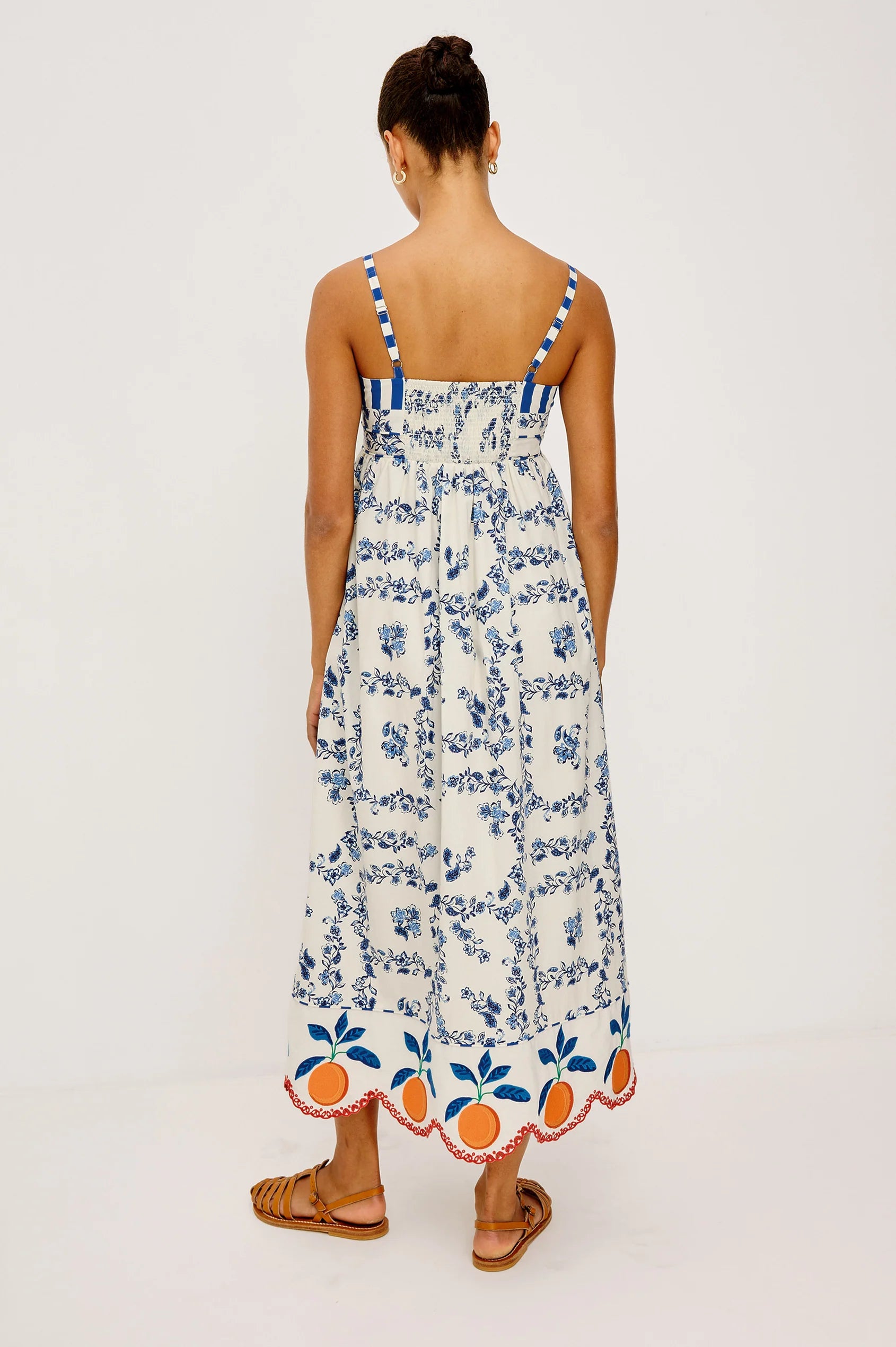 Woman wearing a floral dress with blue and orange details on a white background