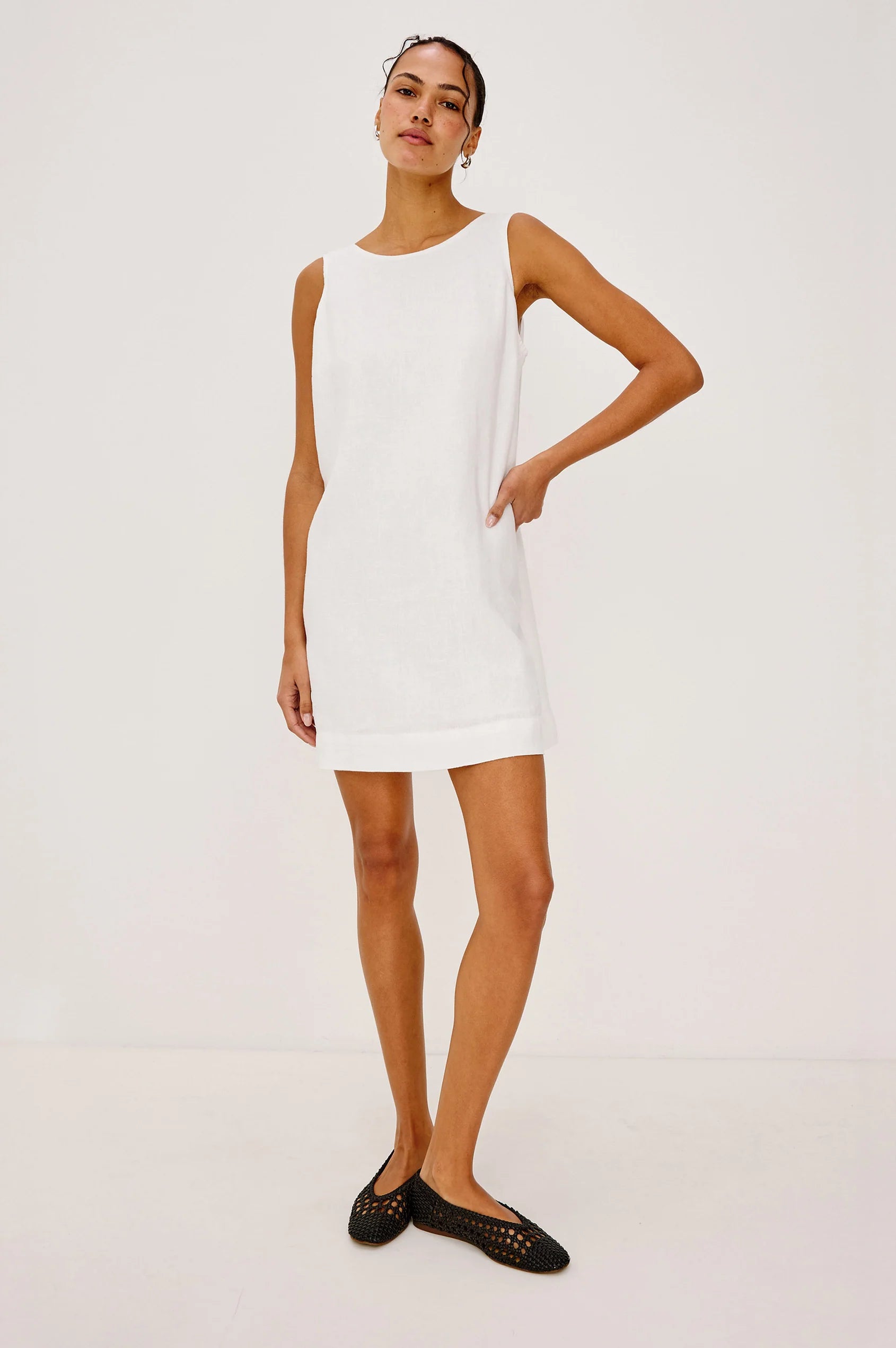 Woman wearing a white sleeveless dress on a plain background