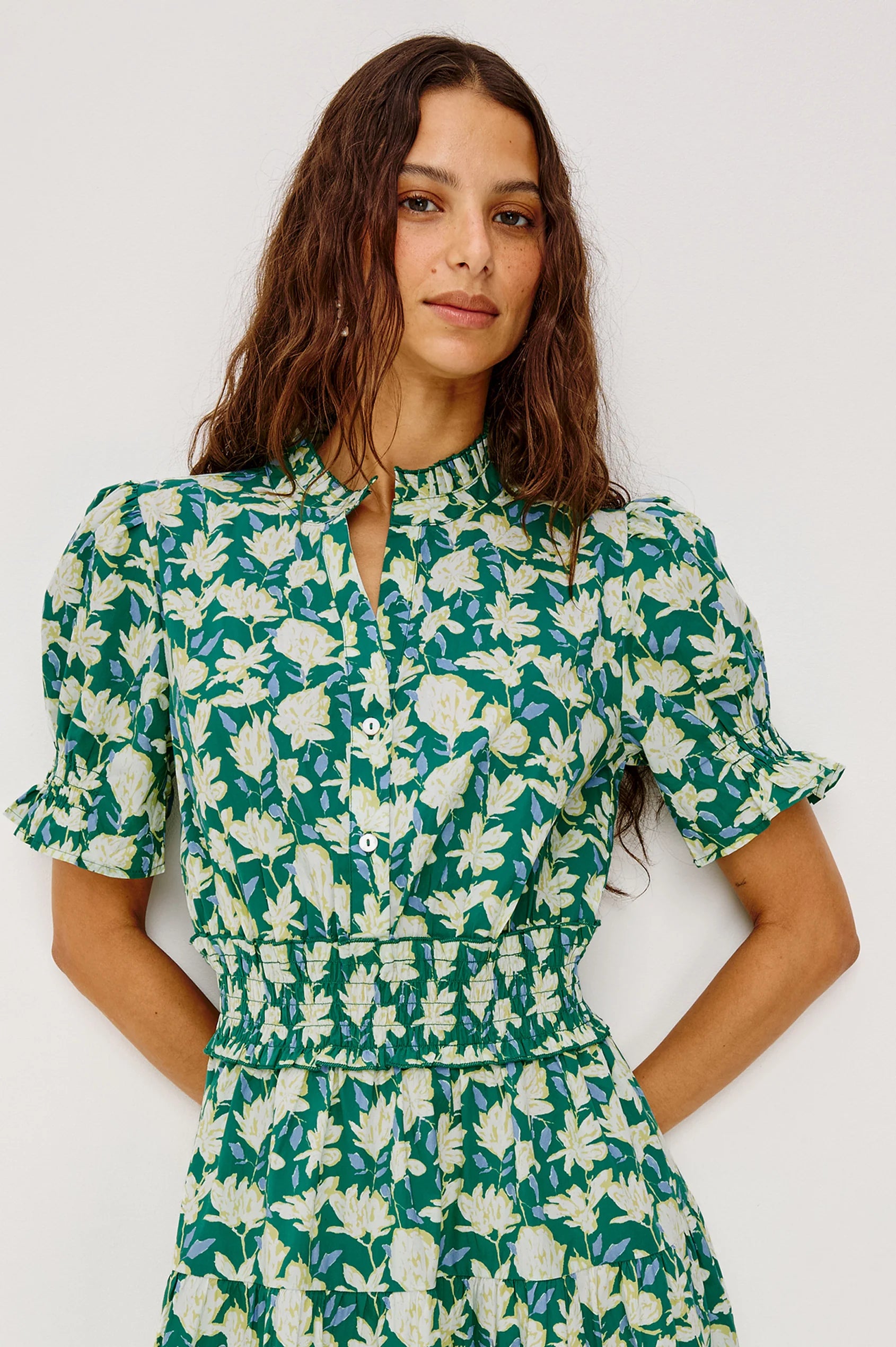 Woman wearing a green floral dress against a white background