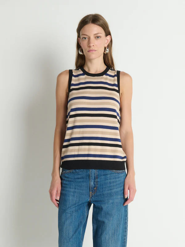 Woman wearing a striped tank top and jeans against a plain background