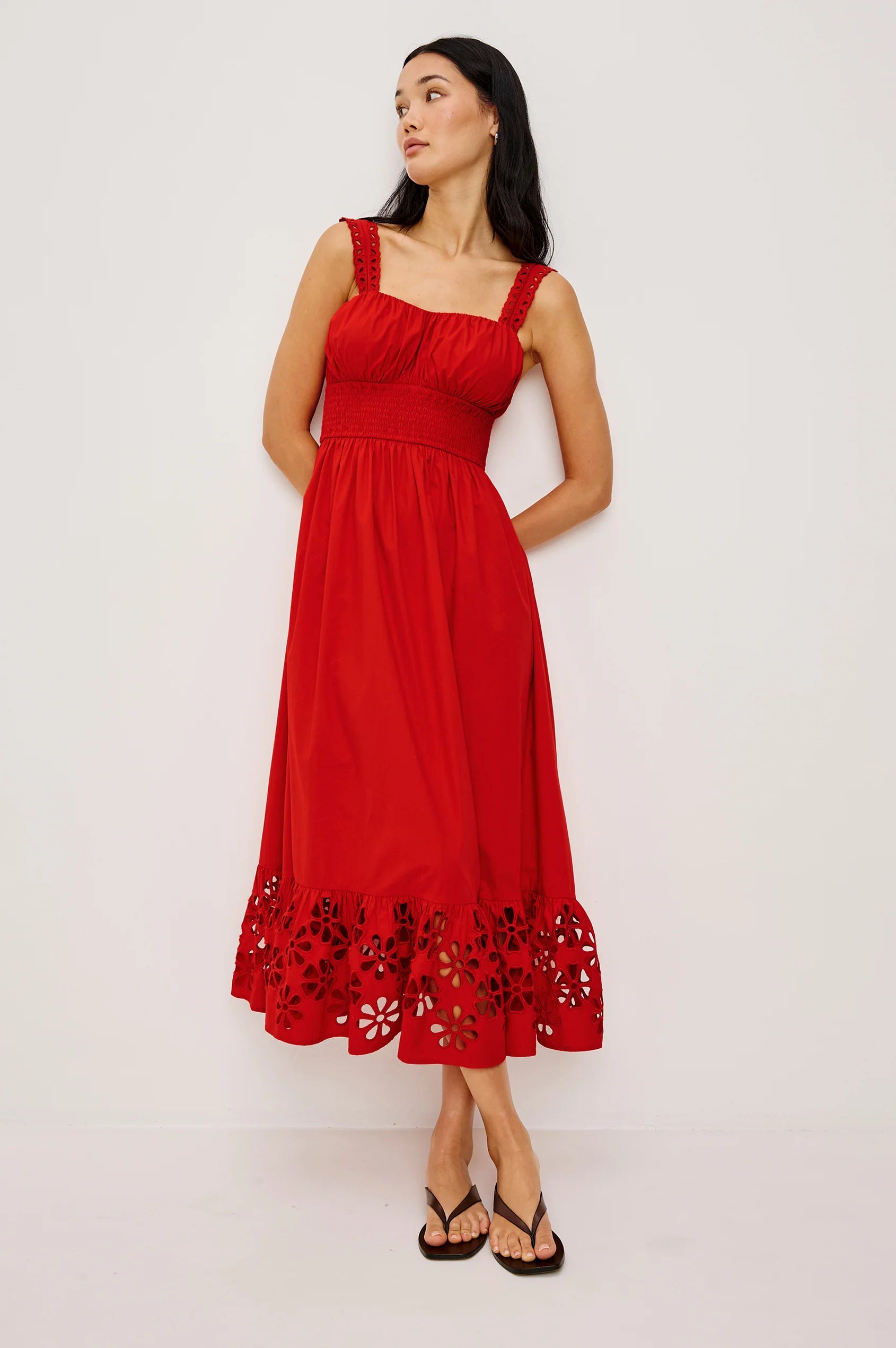 Woman wearing a red dress with floral lace details on a white background
