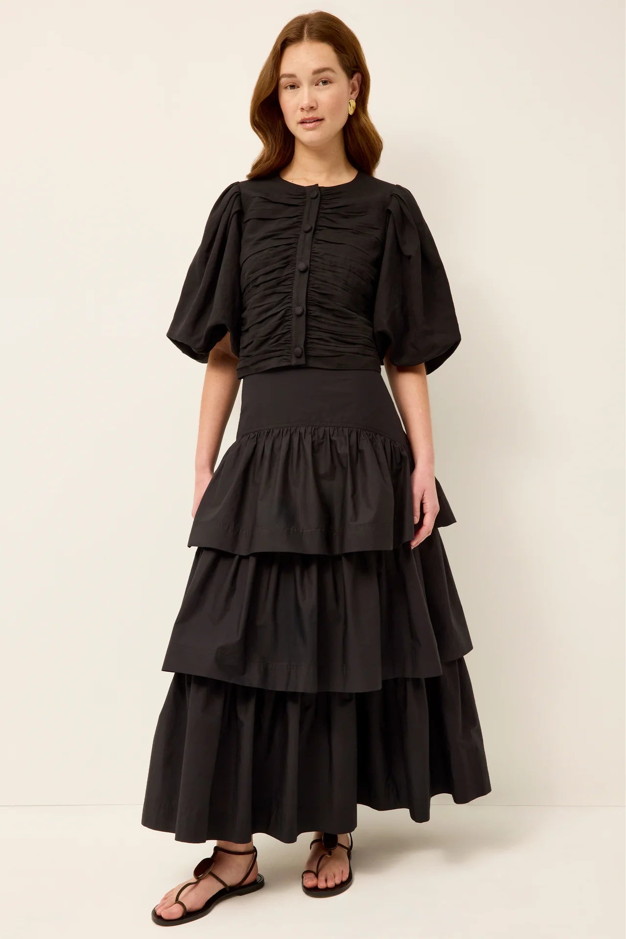 Woman wearing a black tiered dress against a white background