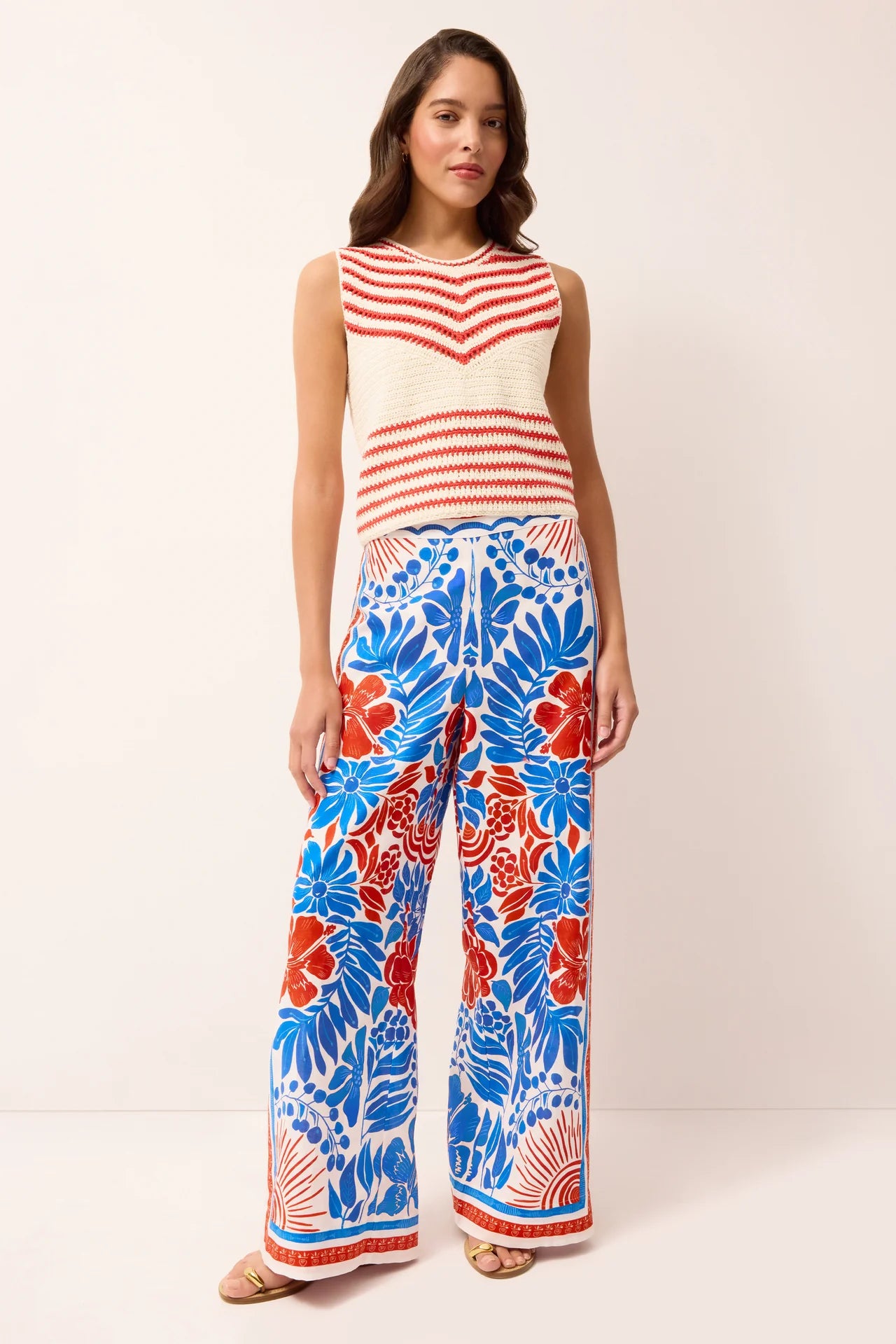 Woman wearing a red and white striped top and blue and red floral pants on a white background