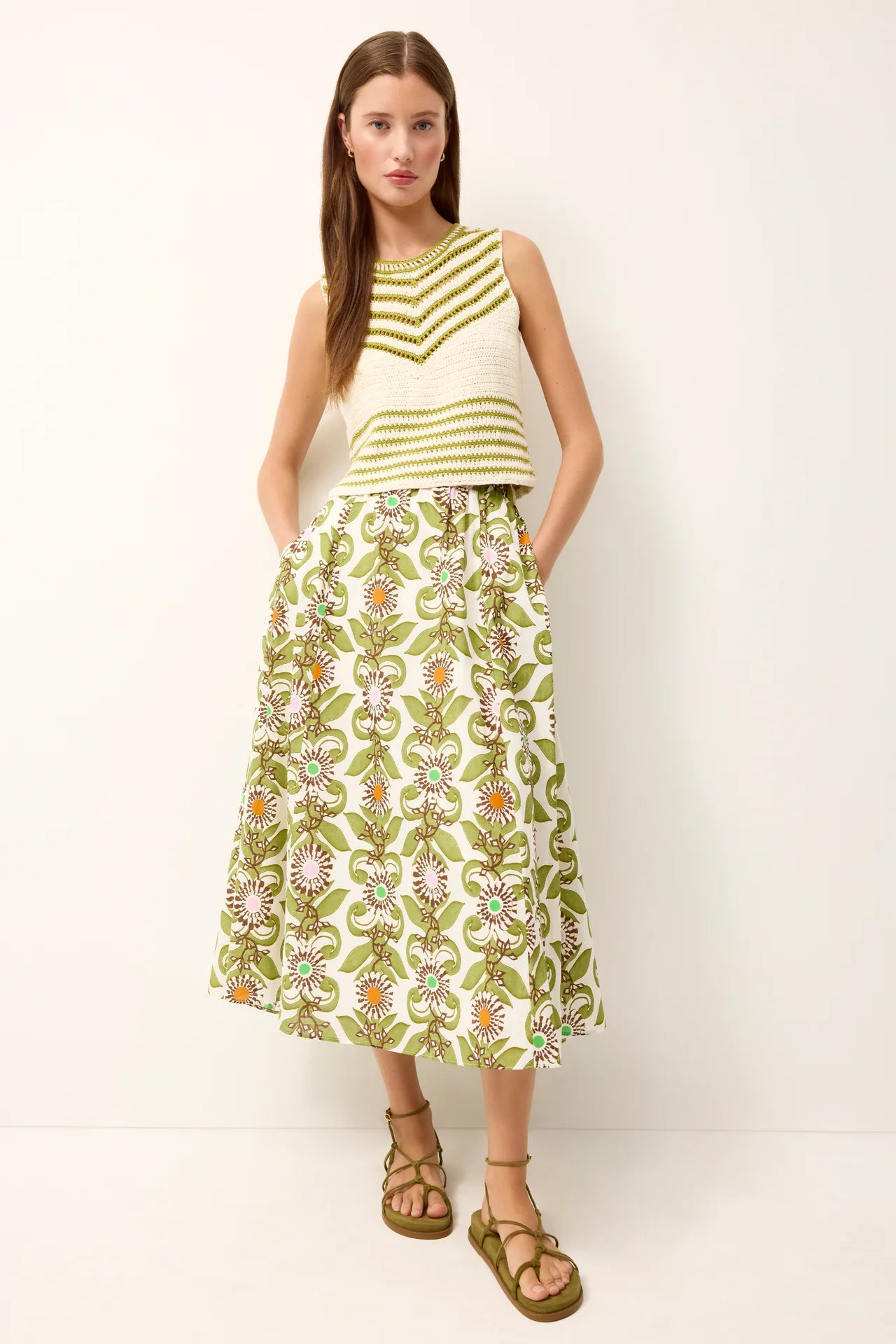 Woman wearing a green and white striped top and floral skirt on a white background