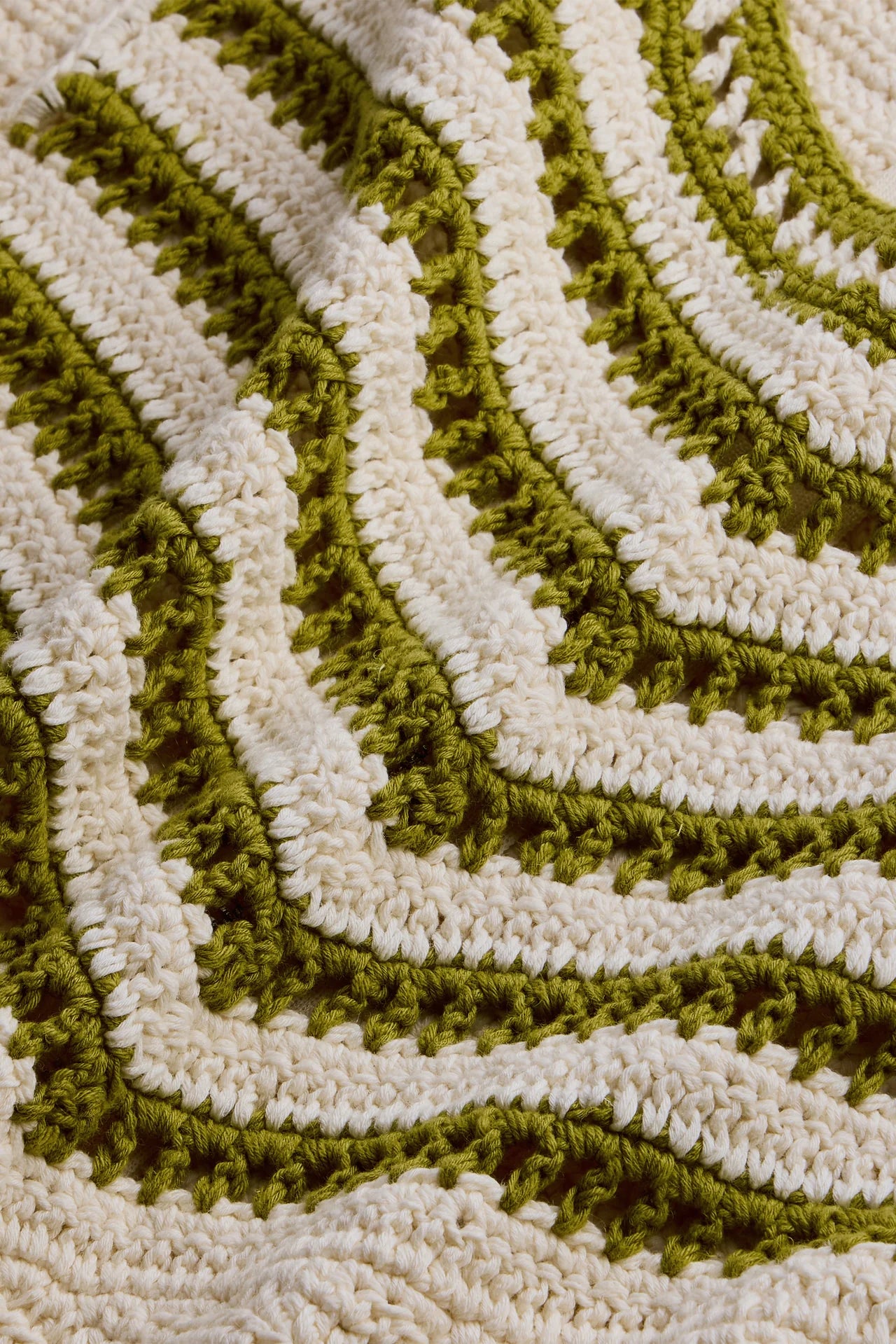 Close-up of a green and beige textured rug with wavy pattern