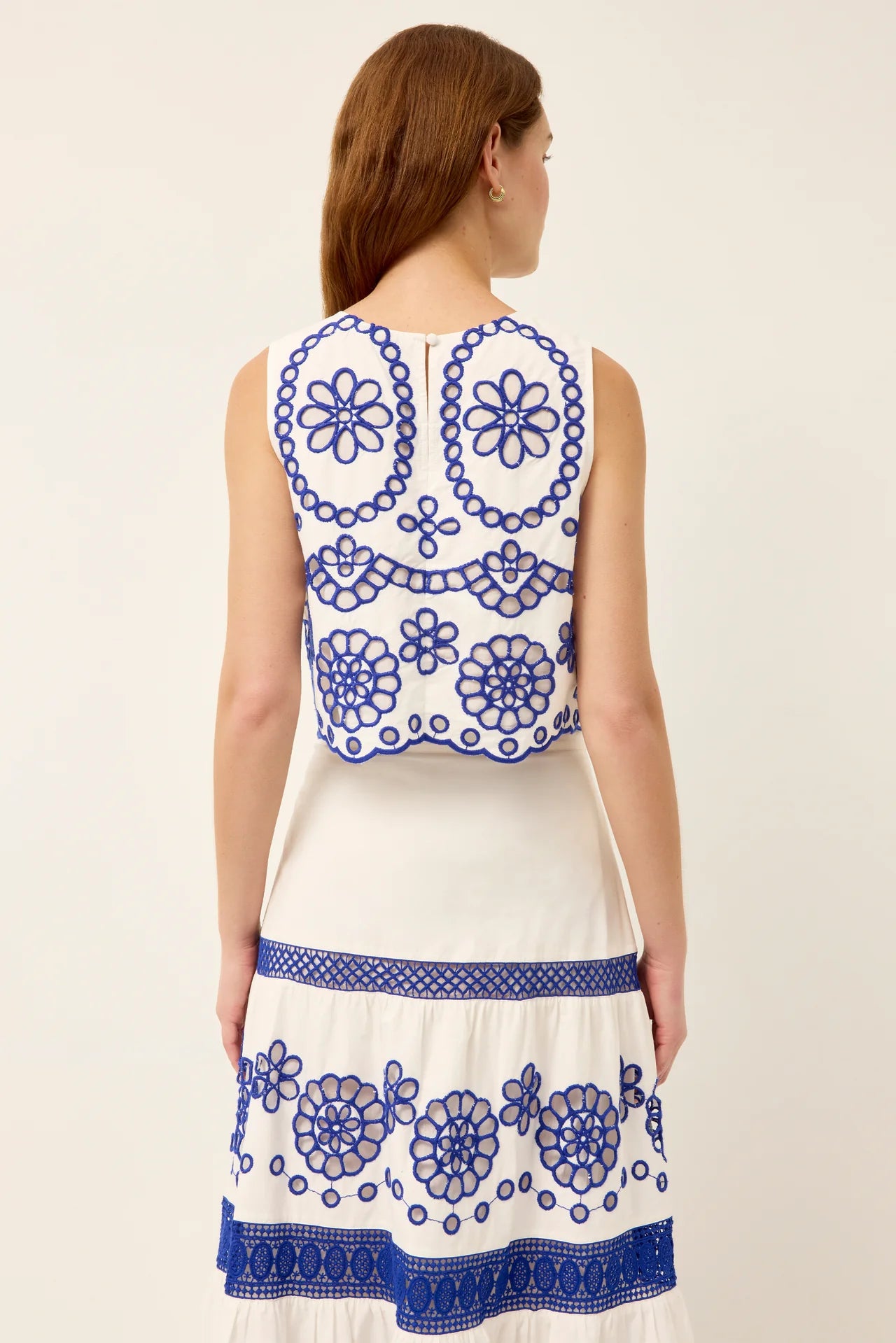 White dress with blue floral embroidery on a plain background