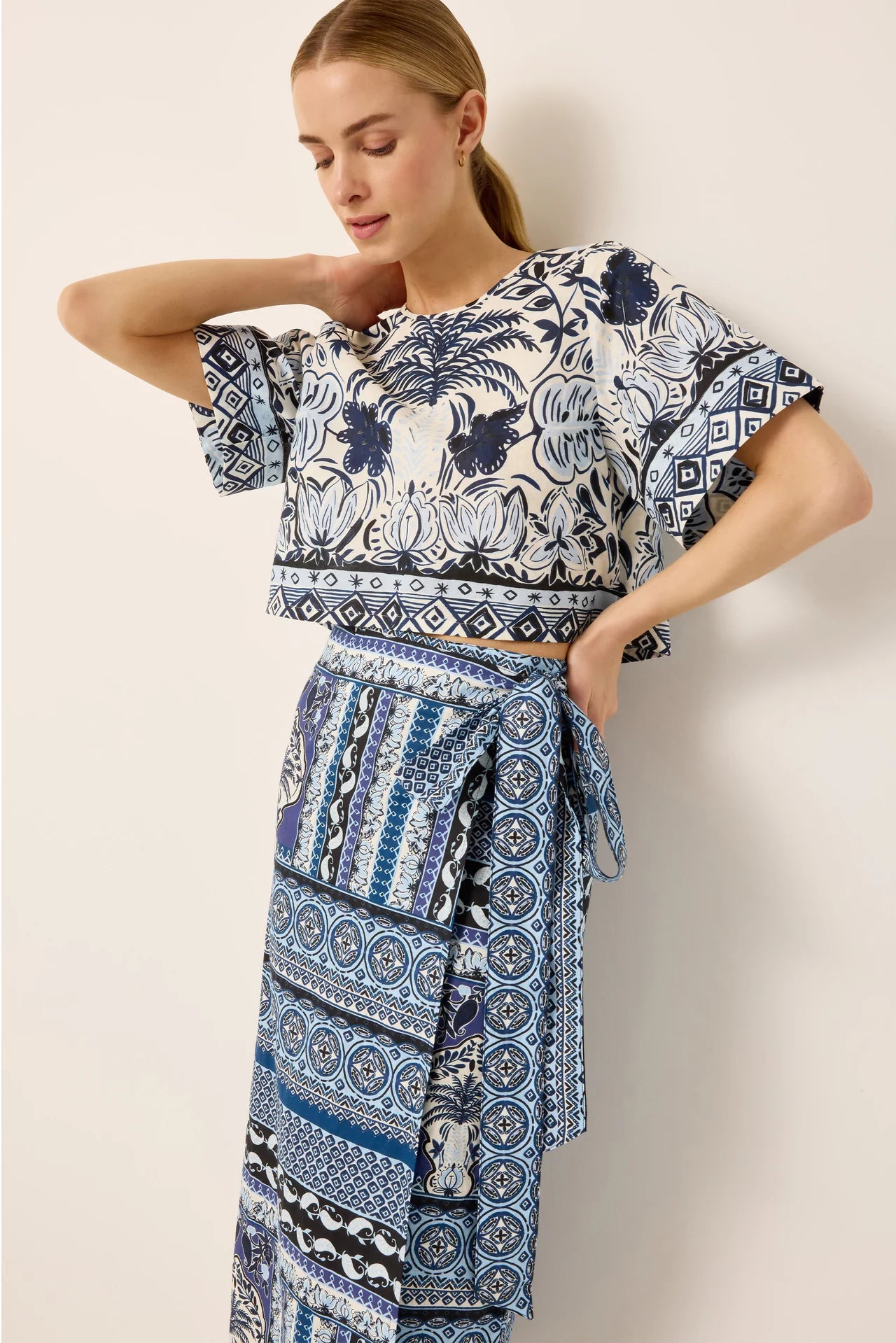 Woman wearing a blue and white patterned outfit against a plain background