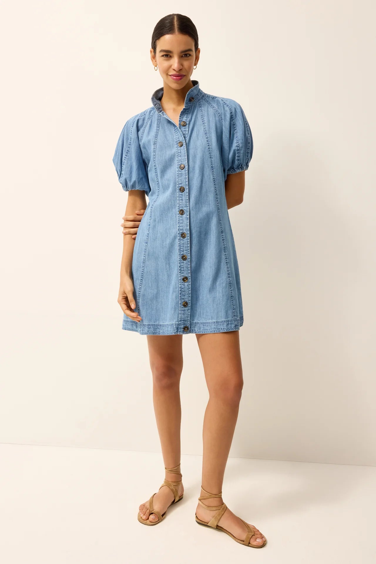 Woman wearing a blue denim dress against a white background