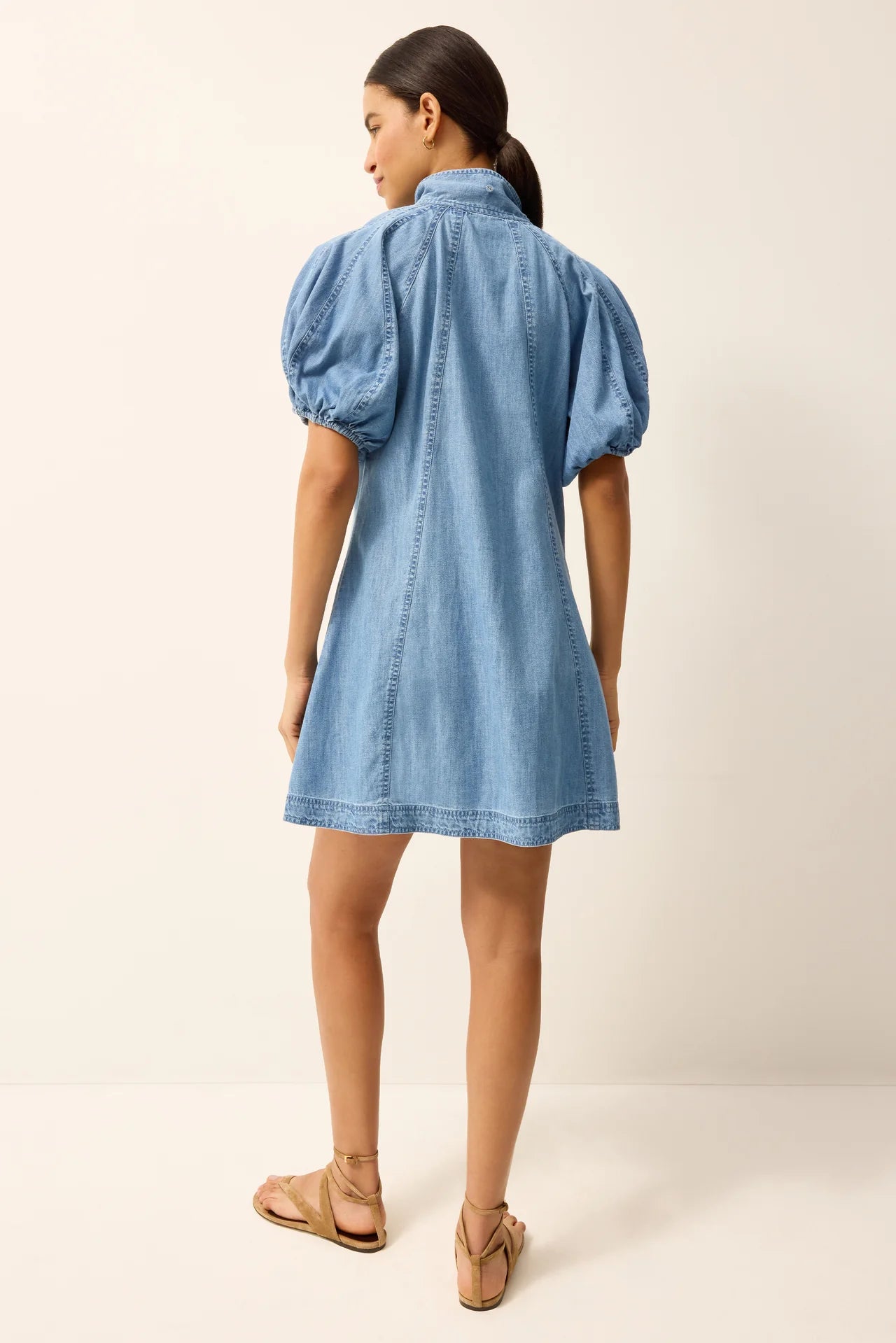 Woman wearing a blue denim dress with puff sleeves on a white background