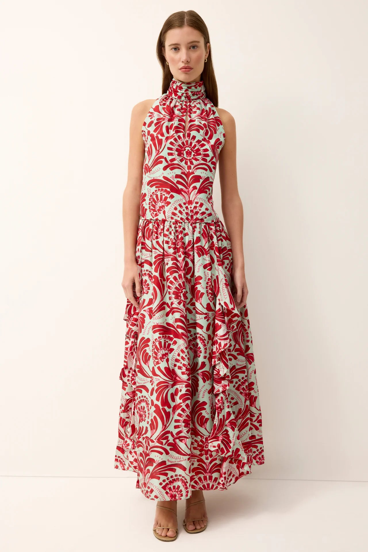 Woman wearing a sleeveless dress with red and white floral pattern on a white background