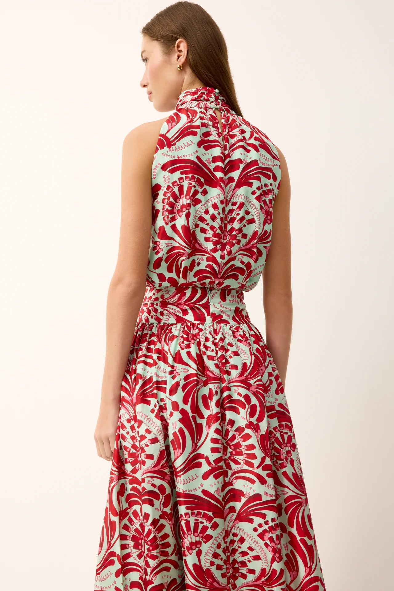 Woman wearing a red and white floral dress against a white background