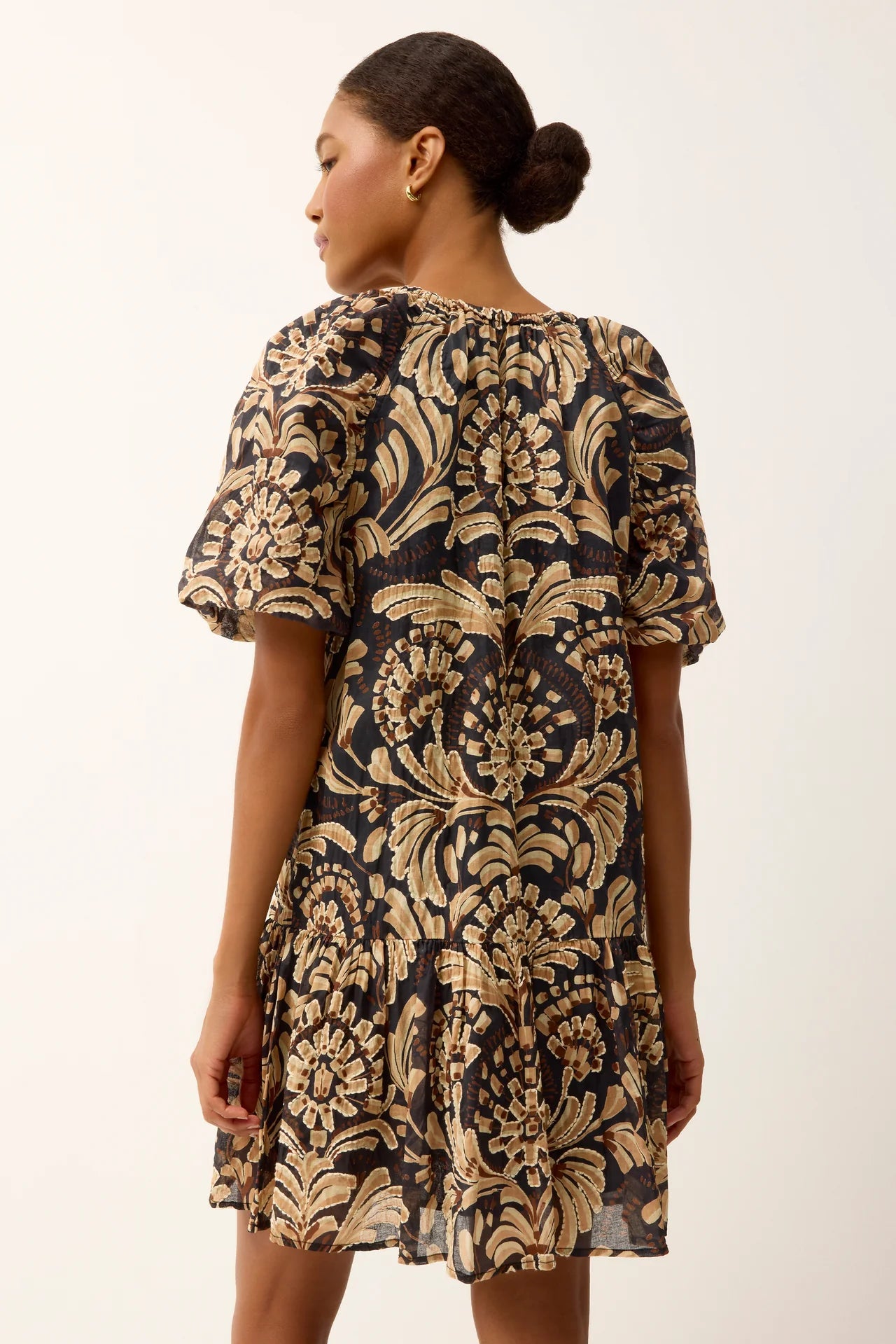 Woman wearing a black and gold floral dress on a white background