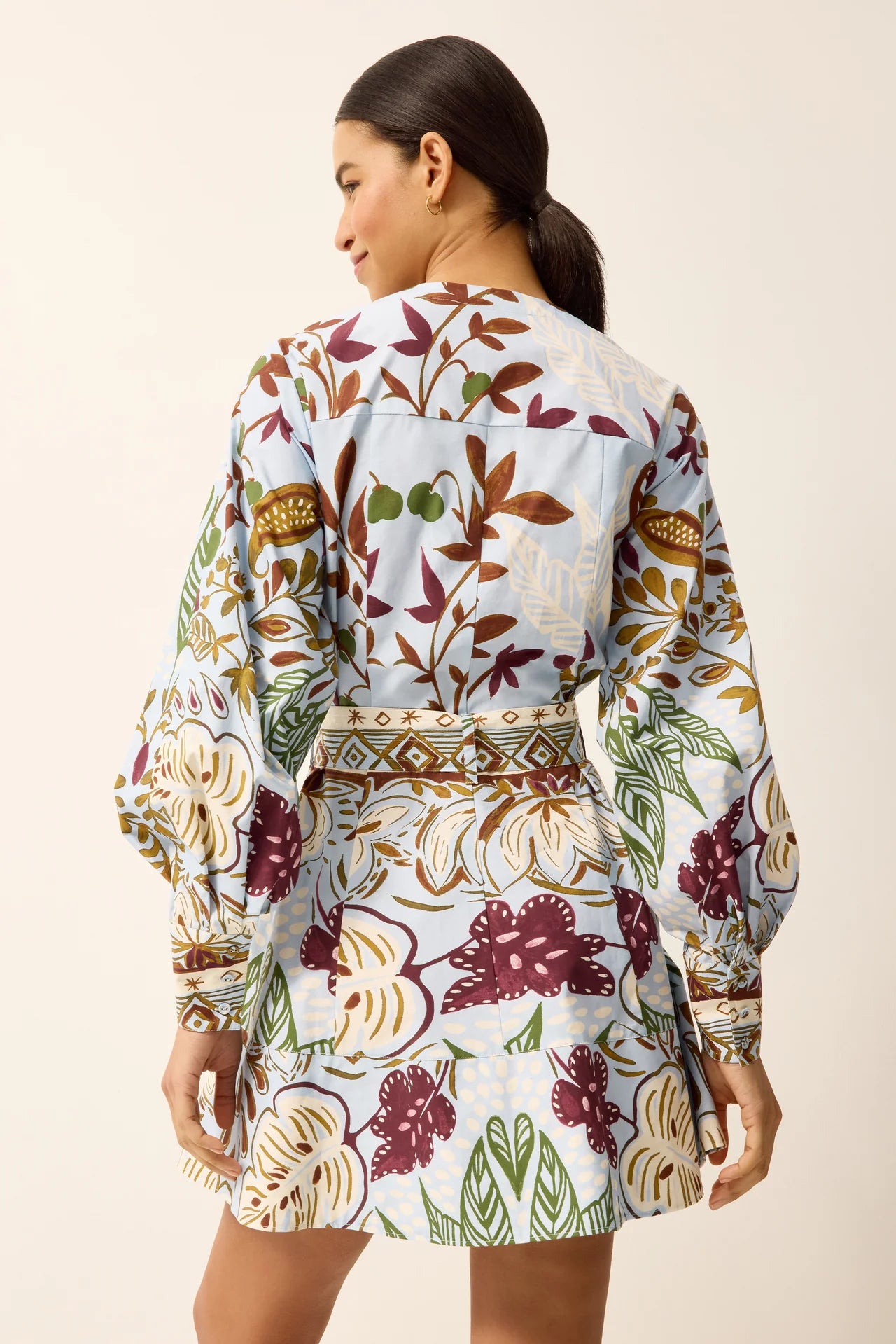 Woman wearing a long-sleeve dress with a floral pattern on a beige background